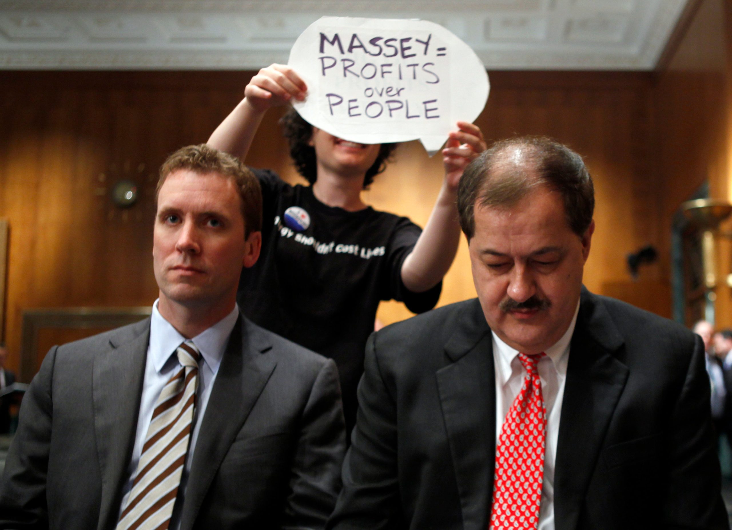 A protester holds a sign behind Vice President of Massey Energy Company and general council Shane Harvey, left, and Massey Energy Company Chief Executive Officer Don Blankenship as they wait to testify on Capitol Hill in Washington, Thursday, May 20, 2010. (Photo: Carolyn Kaster, AP)