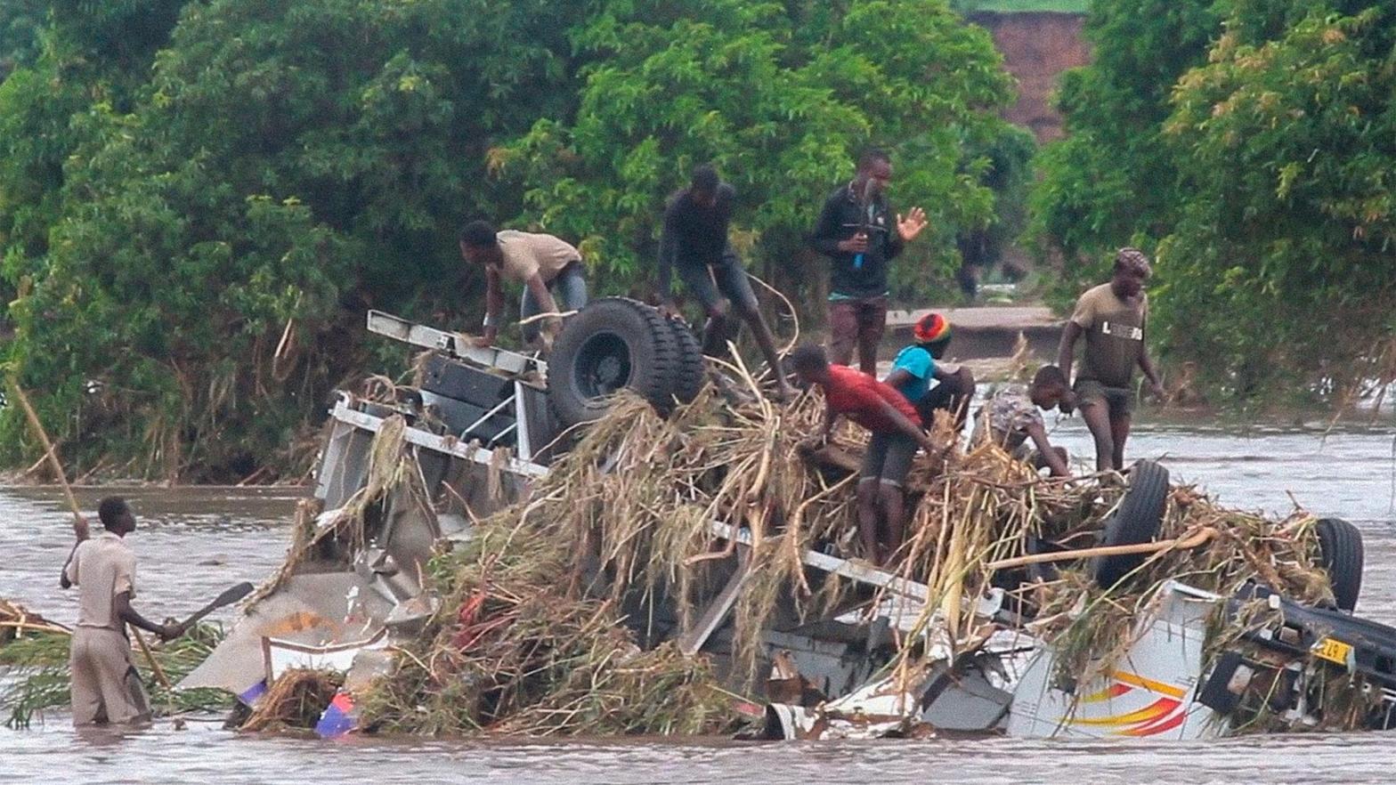 People stand on an overturned vehicle swept by flooding waters in Chikwawa, Malawi, Tuesday Jan. 25. (Photo: AP Photo, AP)