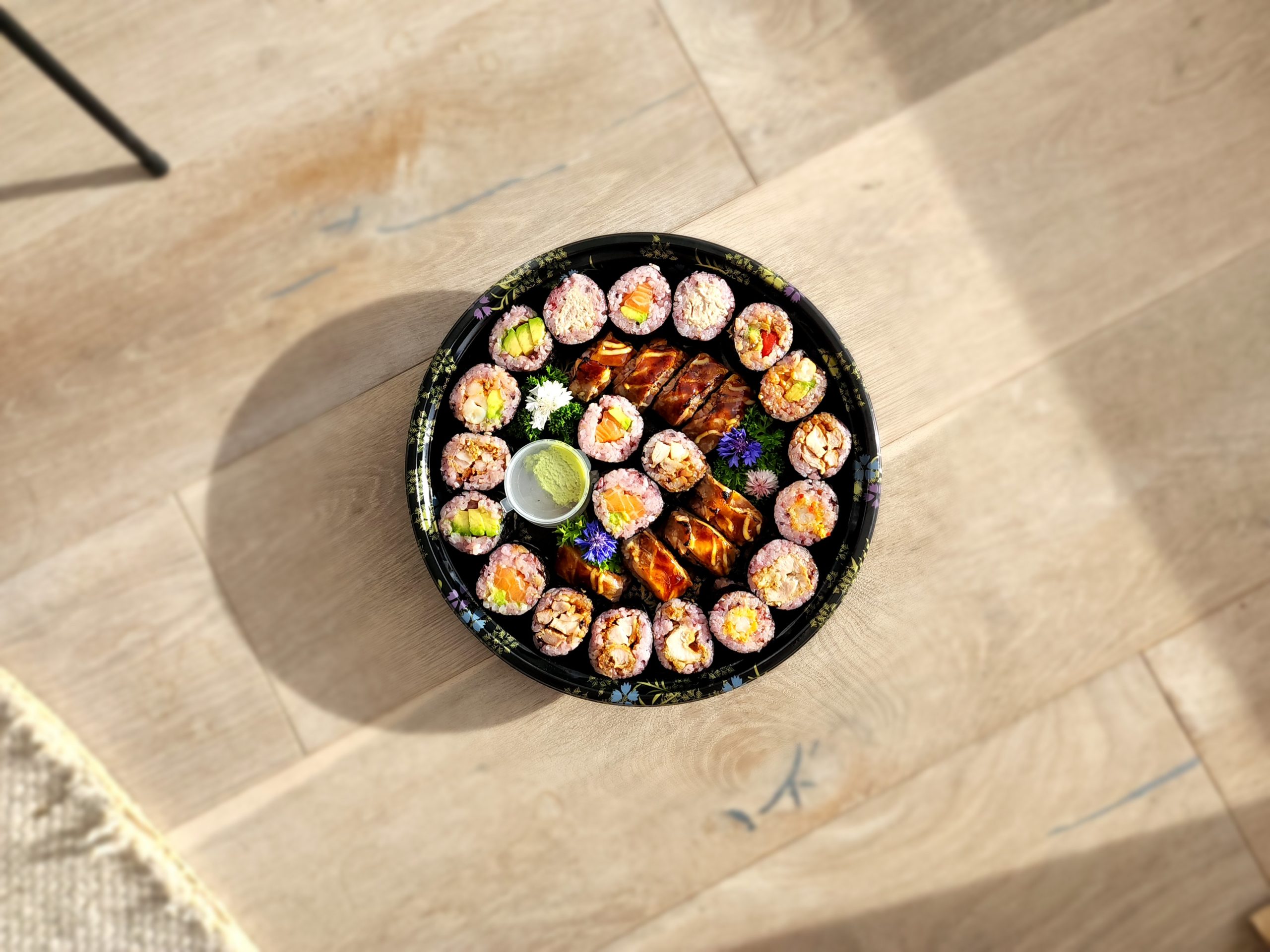 A large platter of sushi on a wooden floor