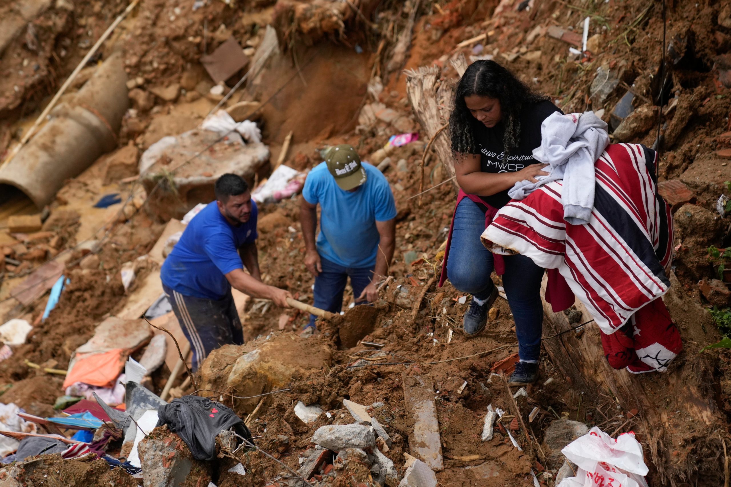 Priscilla Neves recovers belongings while waiting for news about her missing parents, who were in their family home when it was covered by mudslides. (Photo: Silvia Izquierdo, AP)