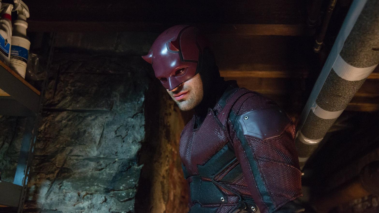 Daredevil grins grimly in his maroon and black armour. (Image: Patrick Harbron/Netflix)