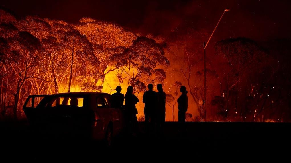 Residents look on as flames burn through bush on January 04, 2020 in Lake Tabourie, Australia.  (Photo: Brett Hemmings, Getty Images)