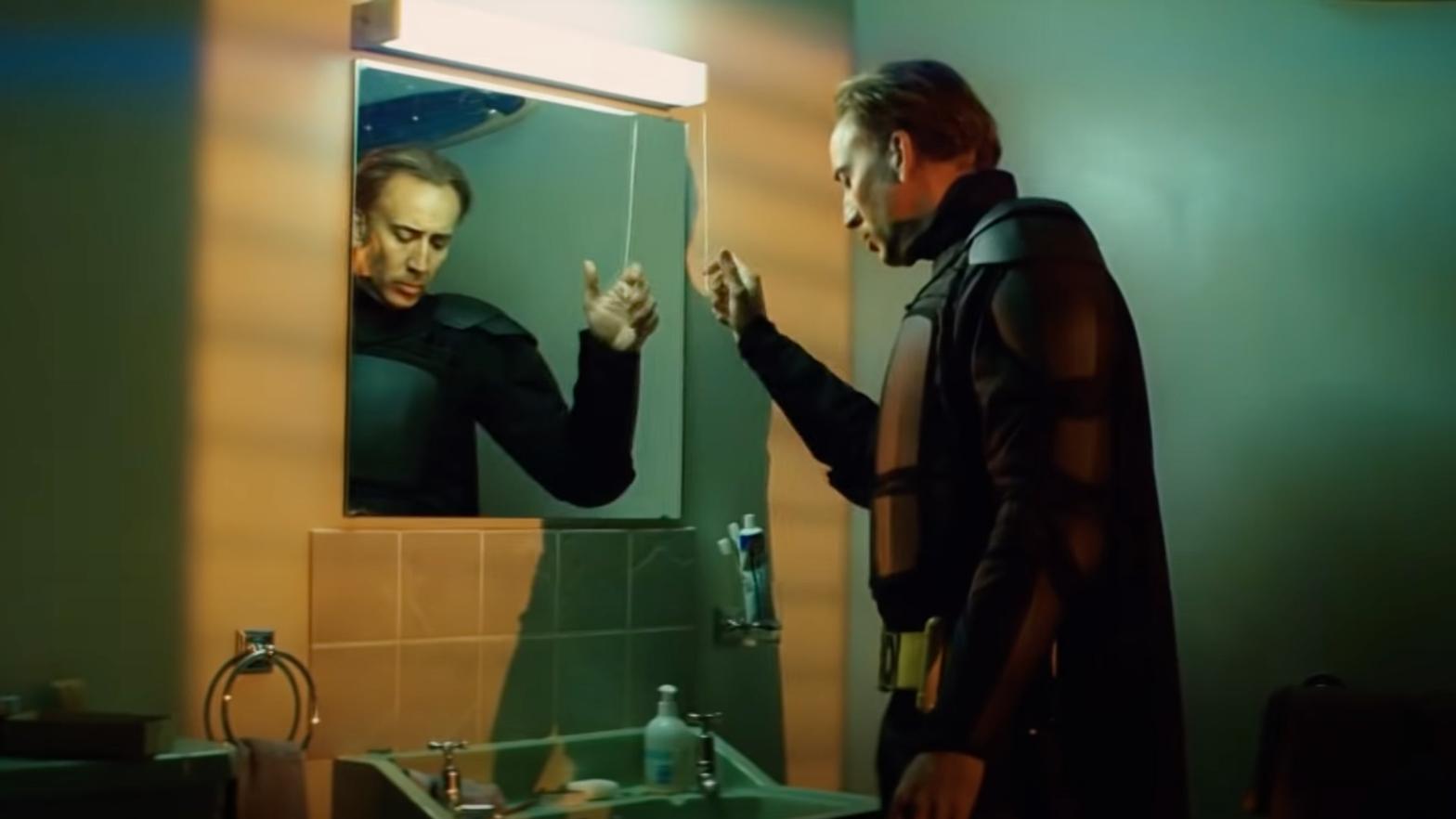 Big Daddy, wearing all of his armour except his mask, turns on a light above a bathroom sink. (Screenshot: Lionsgate)