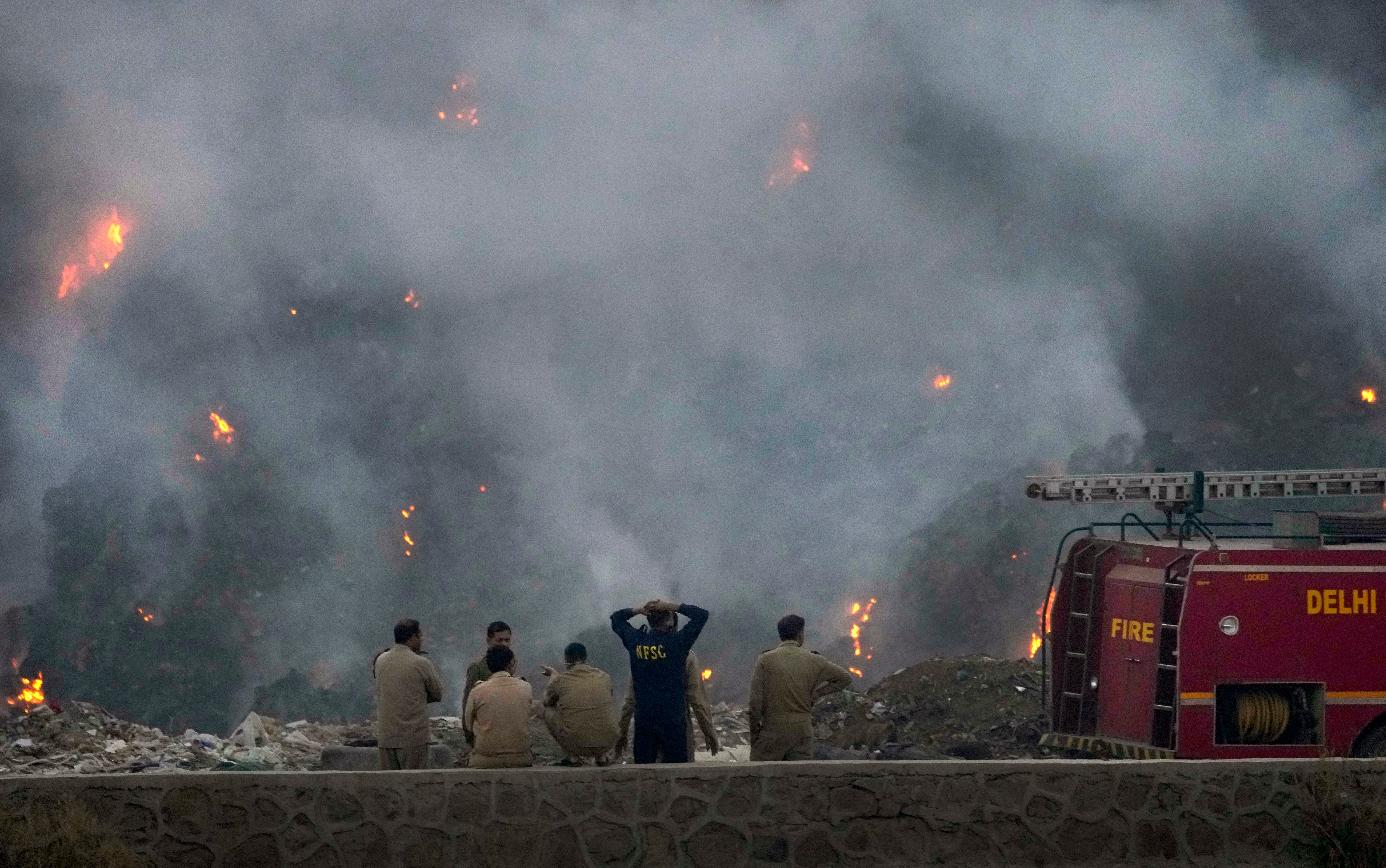 Fire officials look on. (Photo: Manish Swarup, AP)