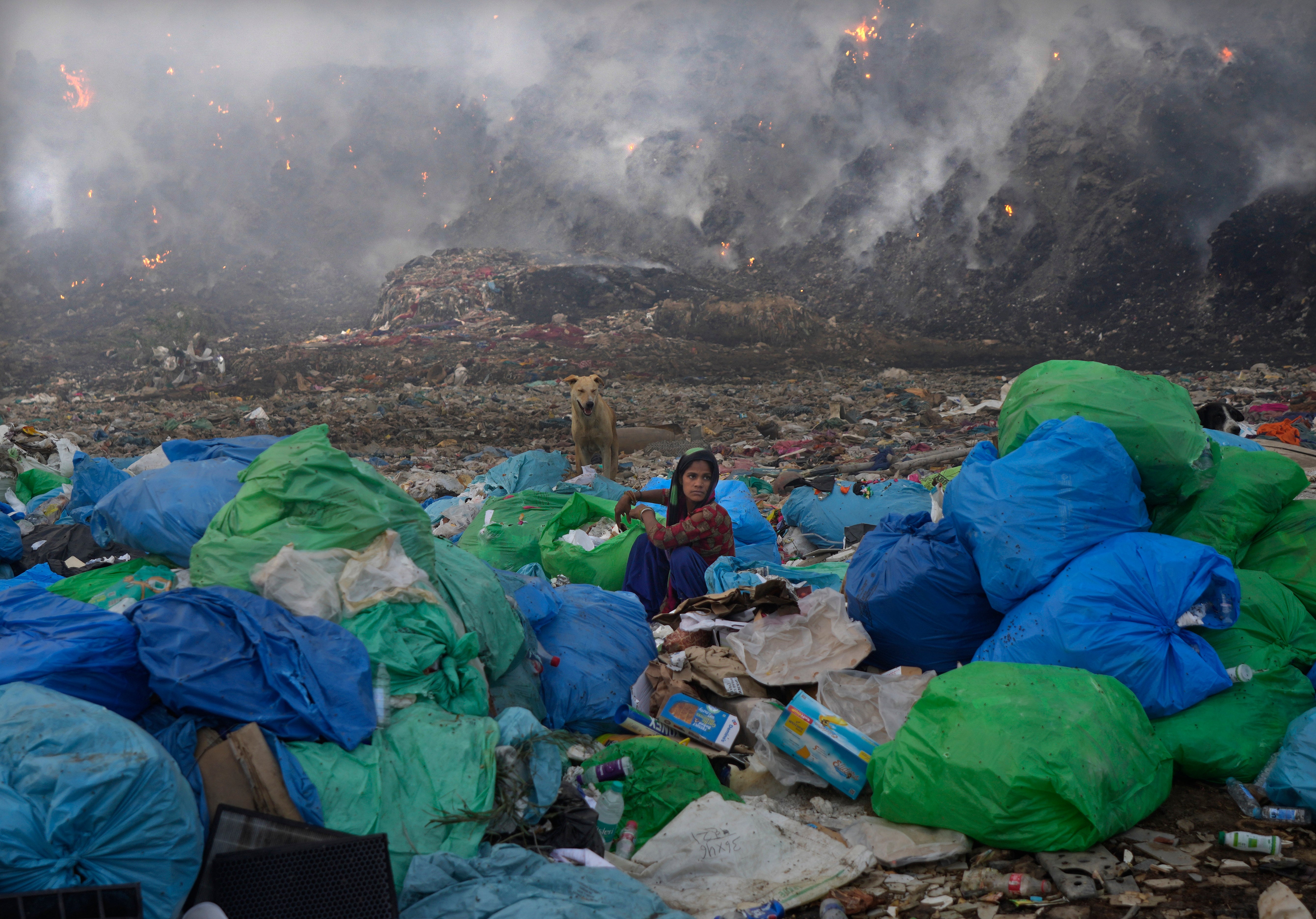 A woman looks for usable items in the landfill as the fire rages around her. (Photo: Manish Swarup, AP)