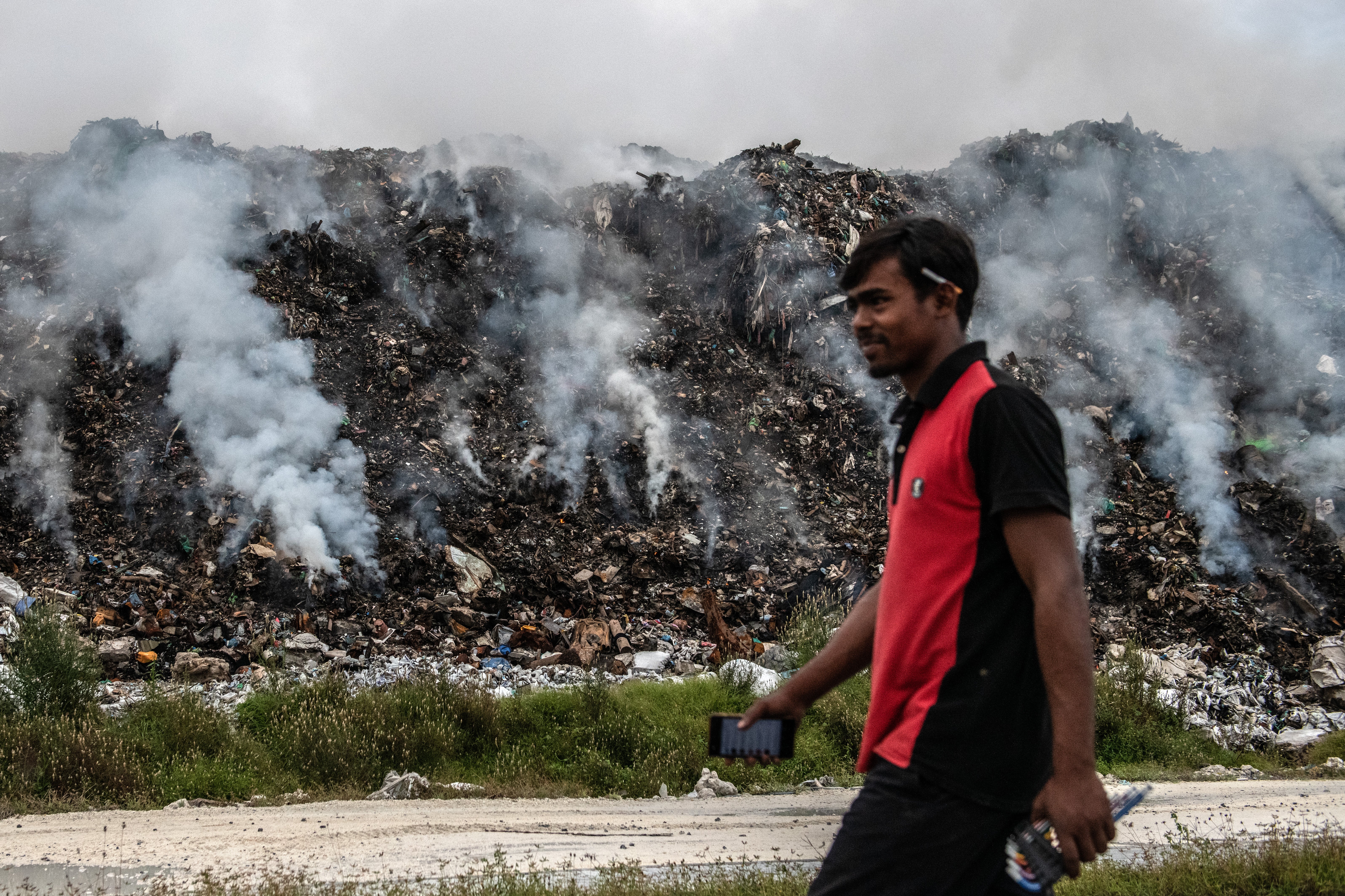 A man walks past smouldering trash on Thilafushi in December of 2019. (Photo: Carl Court, Getty Images)