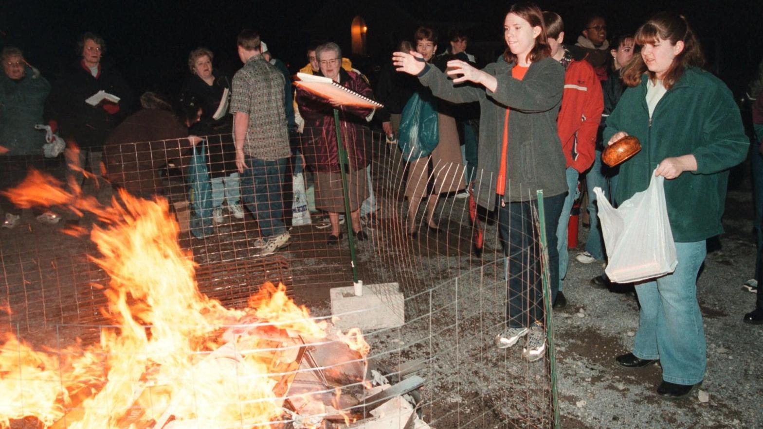 Members of the Harvest Assembly of God Church congregation toss items like books and CDs into a fire in 2001.  (Photo: Butler Eagle, Jack Neely, AP)