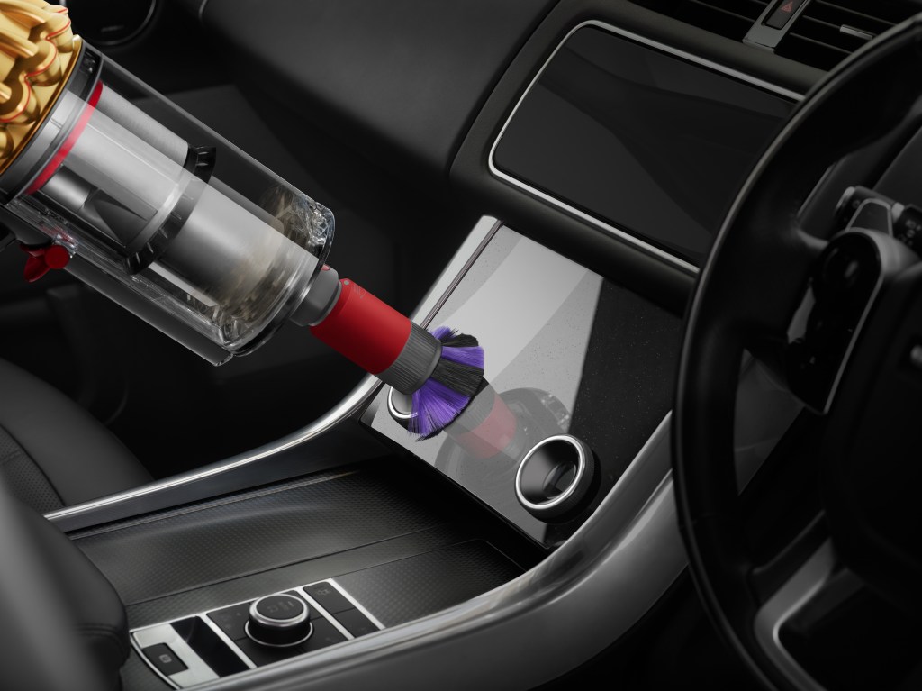 A Dyson attachment cleaning a screen in a car