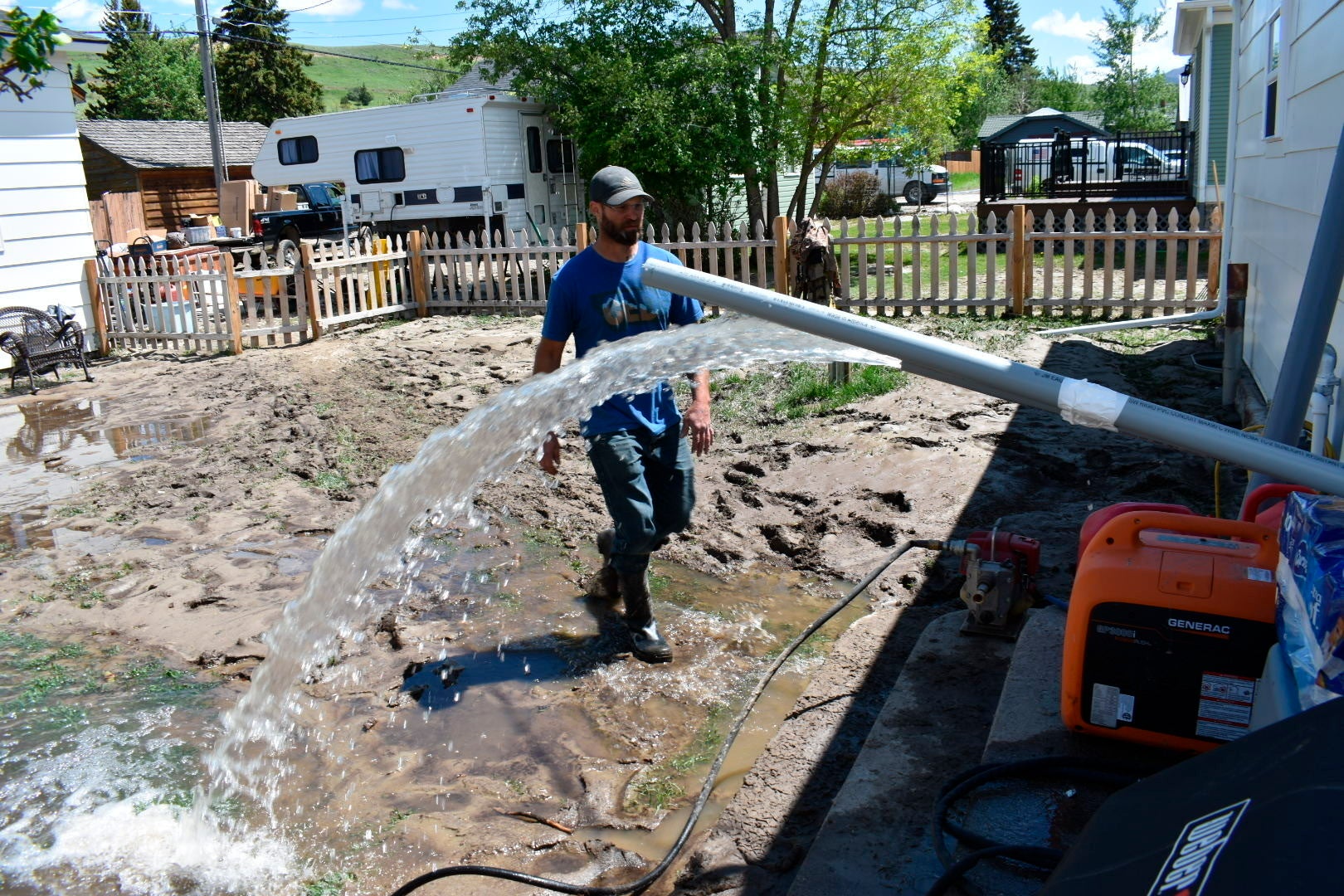 Micah Hoffman is seen in his mud-covered yard as a pump removes water  from his basement, Tuesday June 14, 2022, in Red Lodge, Mont. (Photo: Matthew Brown, AP)