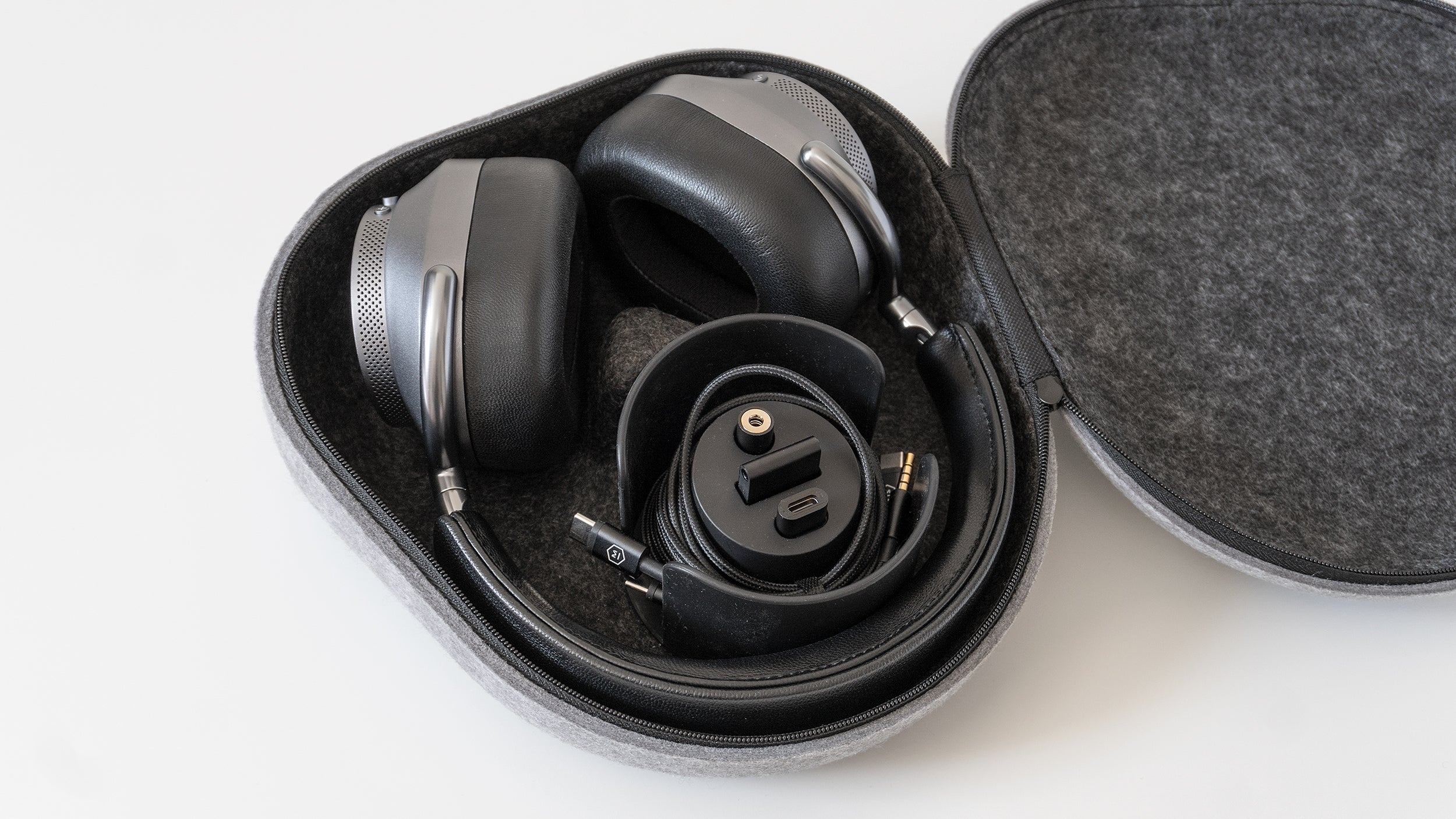 The Master & Dynamic MW75's carrying case includes accessories like a headphone cable, a charging cable, and an adaptor for aeroplane seat headphone jacks. (Photo: Andrew Liszewski | Gizmodo)