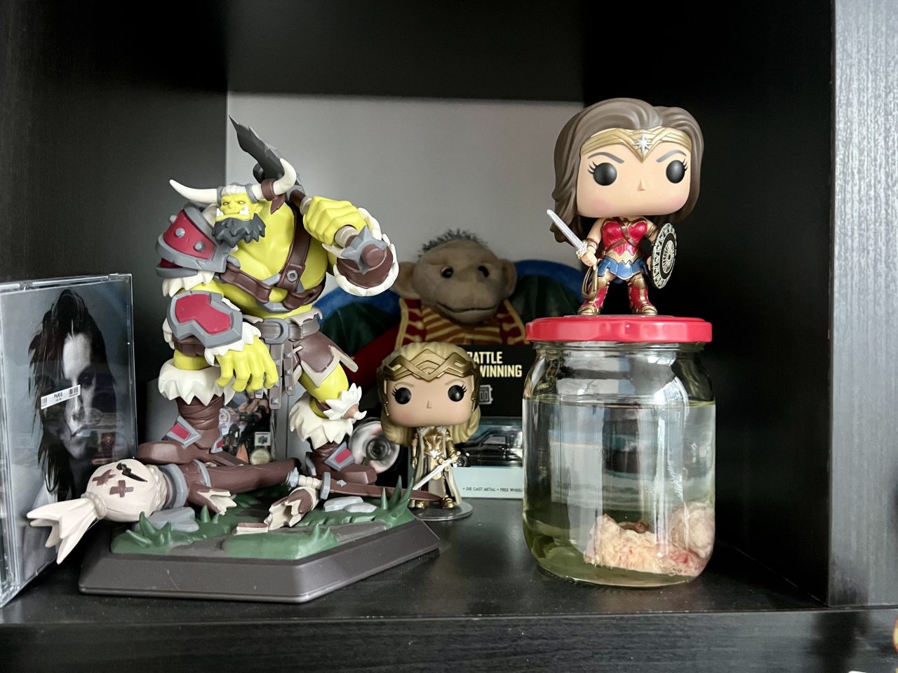 The jar is on a shelf, surrounded by action figures