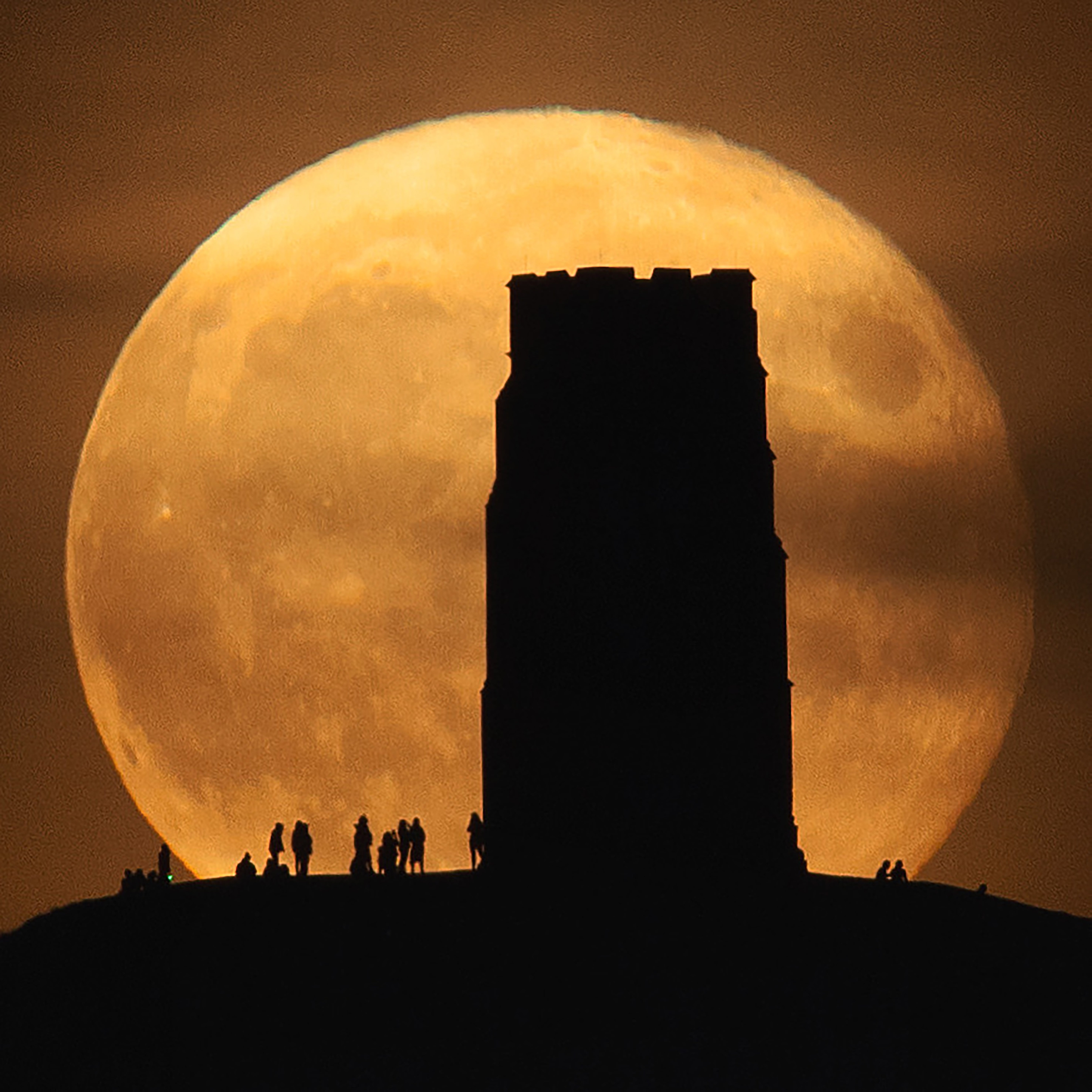 The bright orange harvest moon behind Glastonbury Tor (and onlookers). (Photo: © Hannah Rochford)