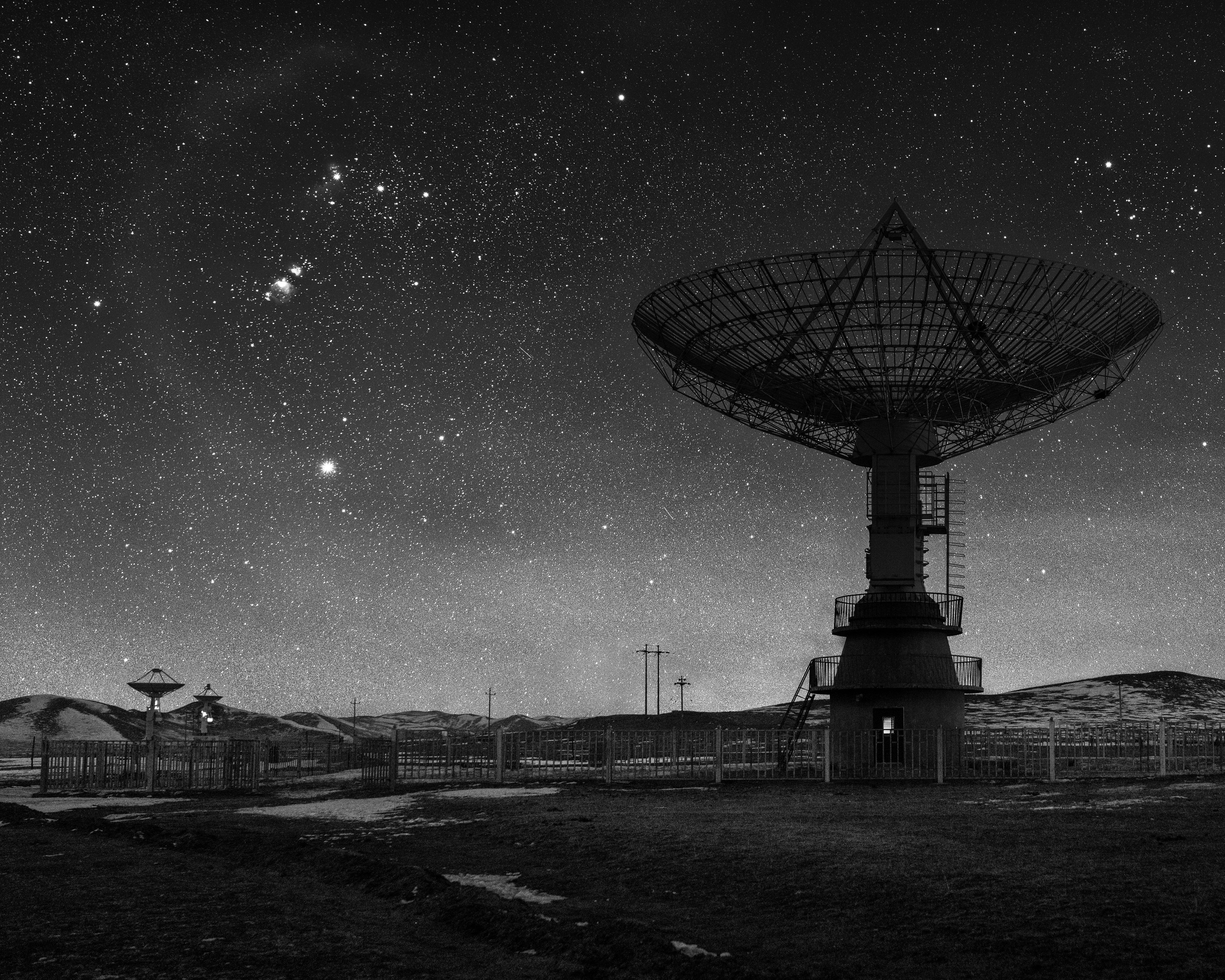 The silhouette of a radio telescope, the cosmos behind it, in black and white. (Photo: © Liu Xuemei)