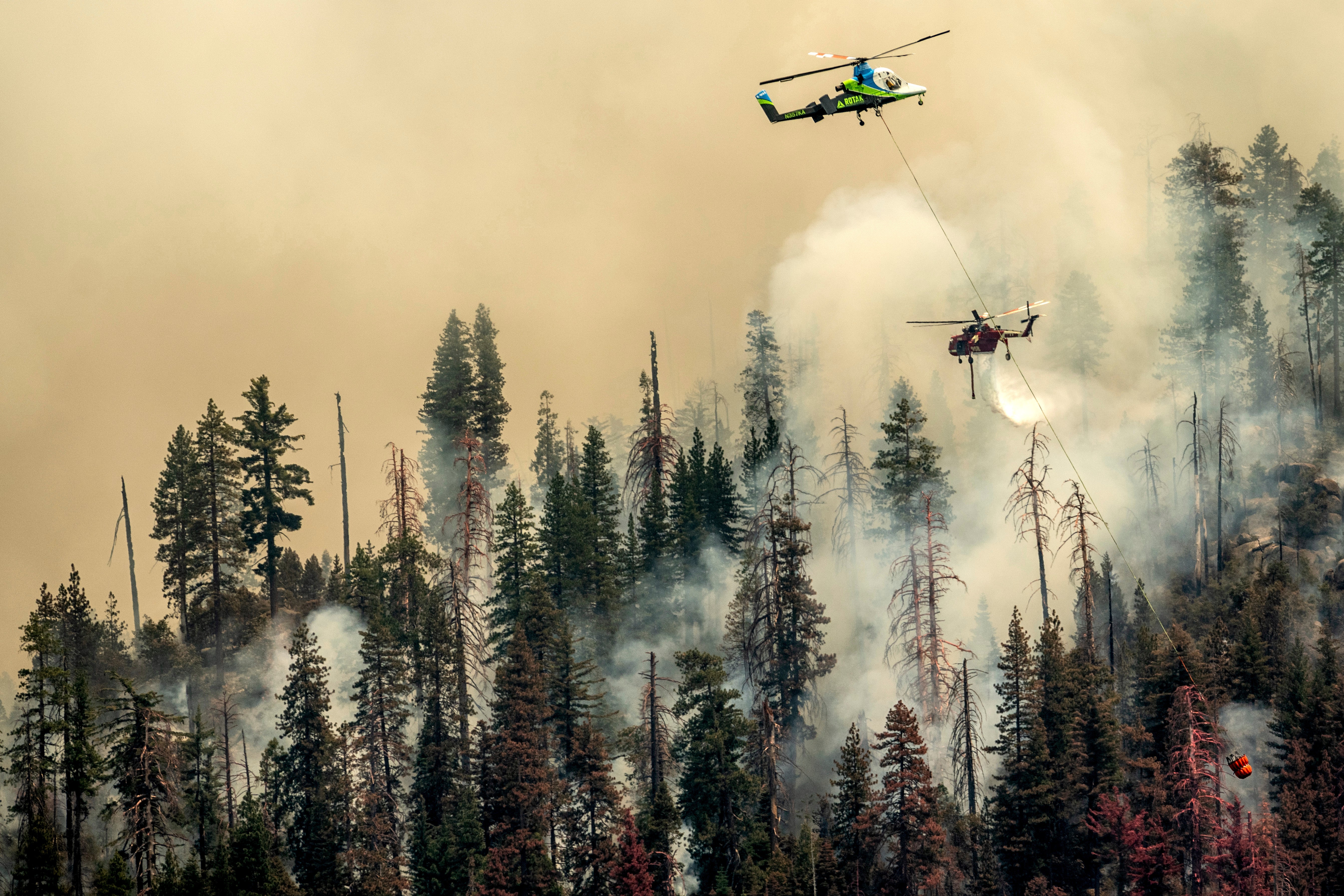 A helicopter drops water on the Washburn Fire burning through Yosemite National Park on Saturday, July 9. (Photo: Noah Berger, AP)