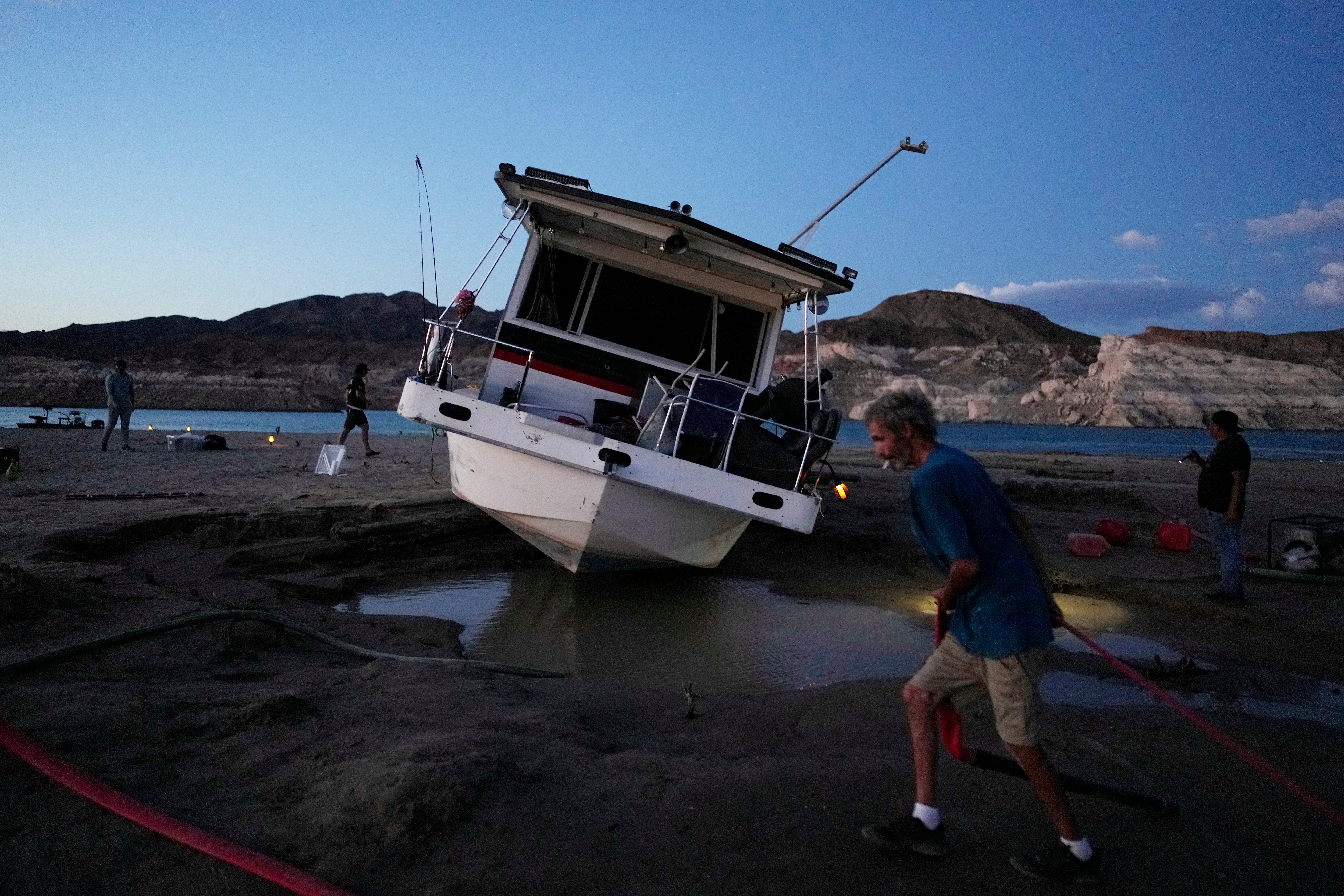 A man tries to free his stranded houseboat on Lake Mead. (Photo: John Locher, AP)