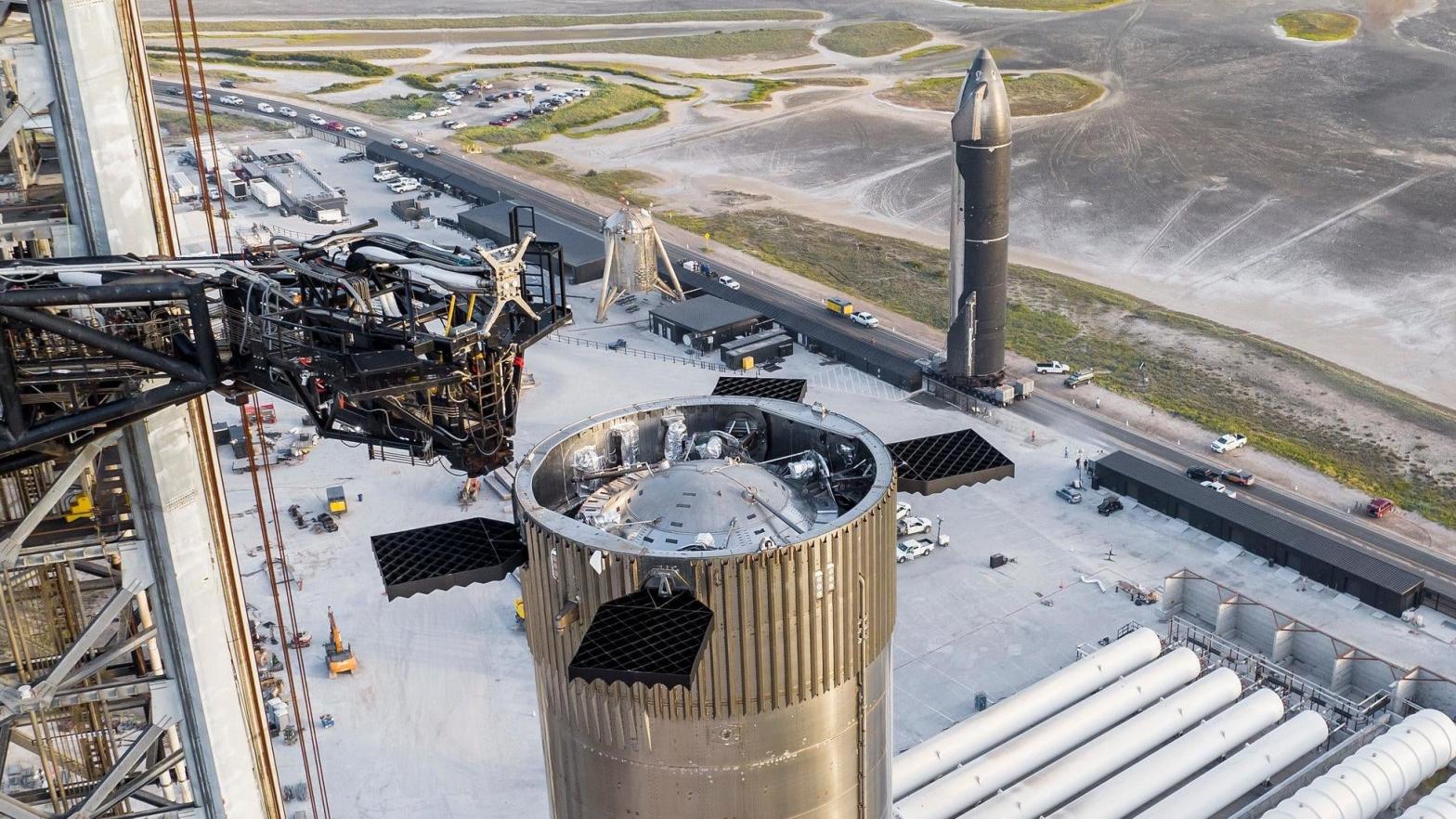 The Super Heavy Booster 7 prototype at the launch mount, with Starship 24 upper stage in the background.  (Photo: SpaceX)
