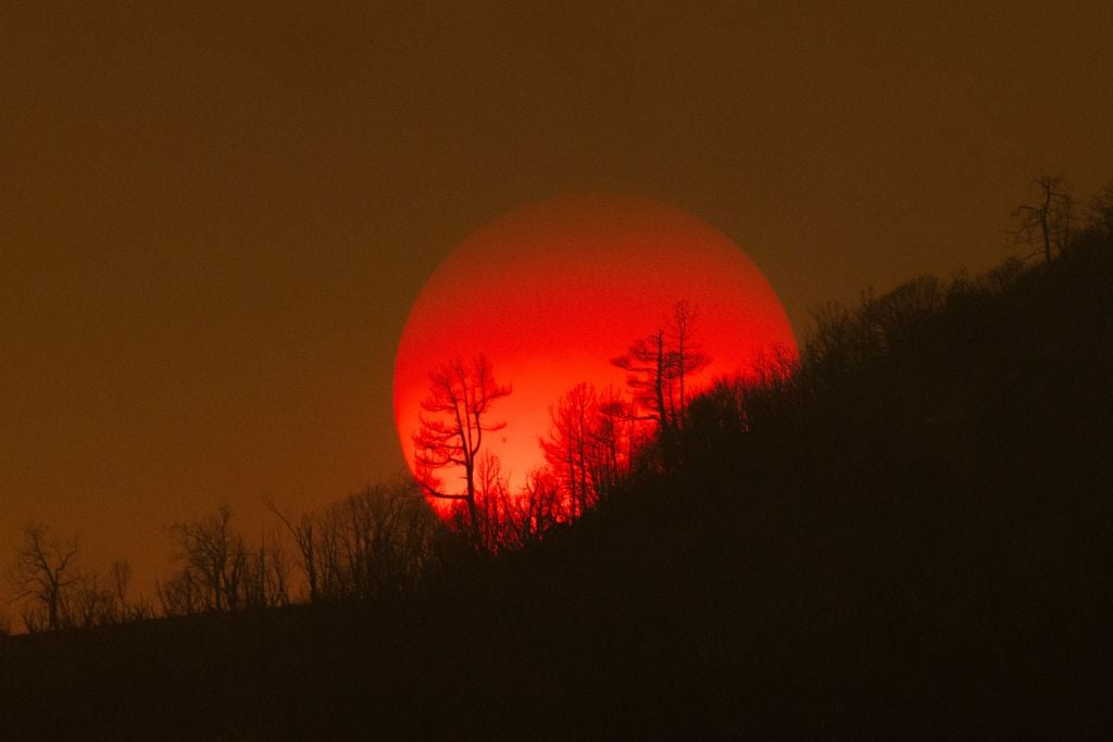 The sun sinks behind a smoky sky and burned forest at the Oak Fire on near Mariposa, California, on July 24, 2022. (Photo: DAVID MCNEW/AFP, Getty Images)