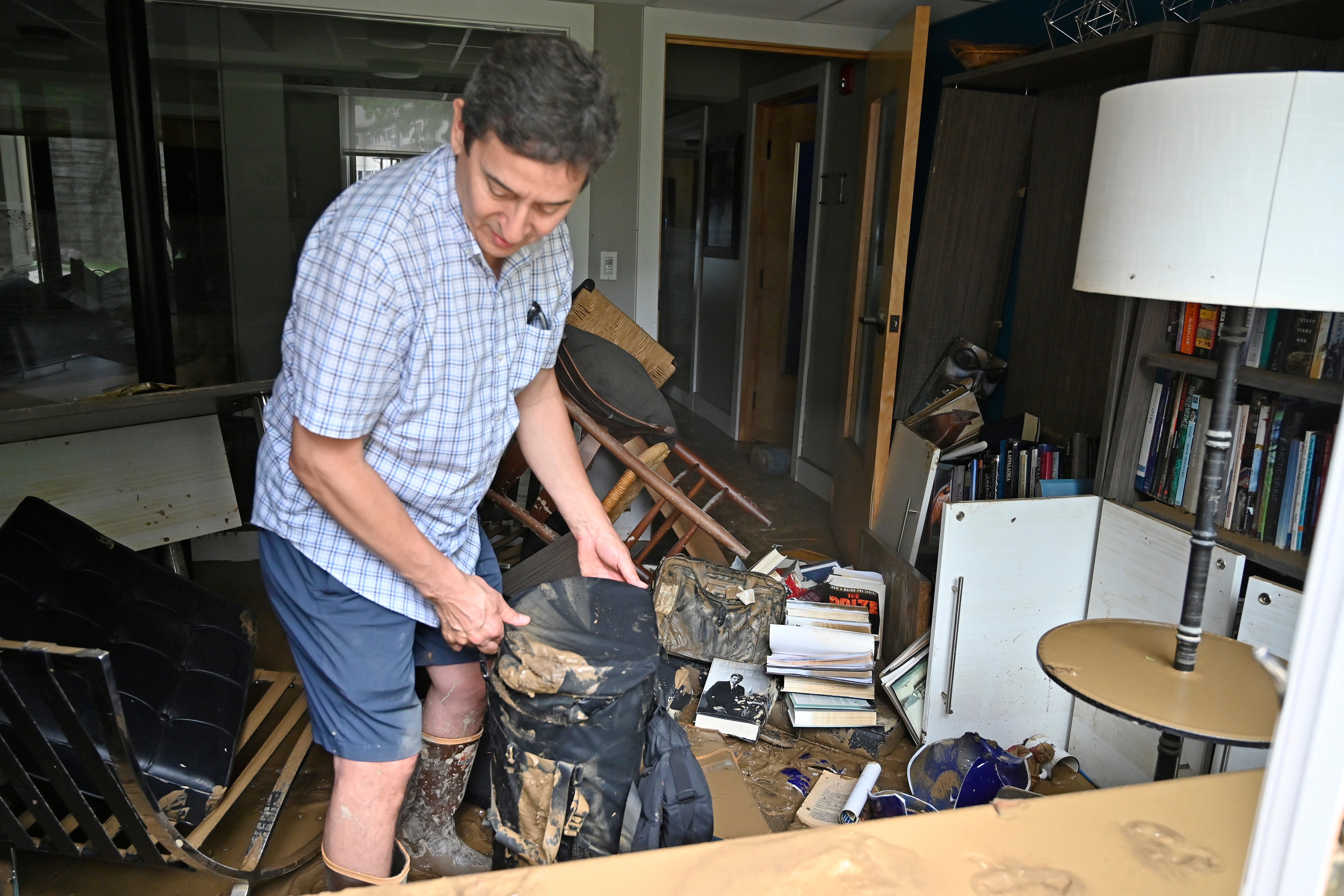 Will Anderson, Director of the Hindman Settlement School sorts through  the mud covered objects in his office in Hindman, Ky., Friday, July 29,  2022. (Photo: Timothy D. Easley, AP)