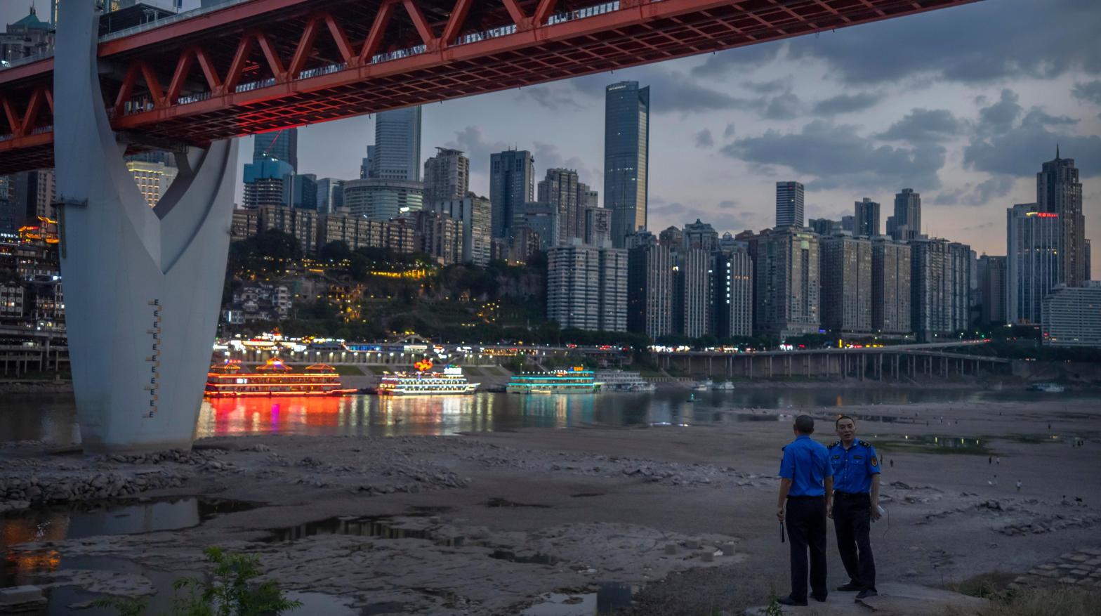 Security officers stand in the dried-out riverbed of the Jialing River in Chonqing on August 20. (Photo: Mark Schiefelbein, AP)