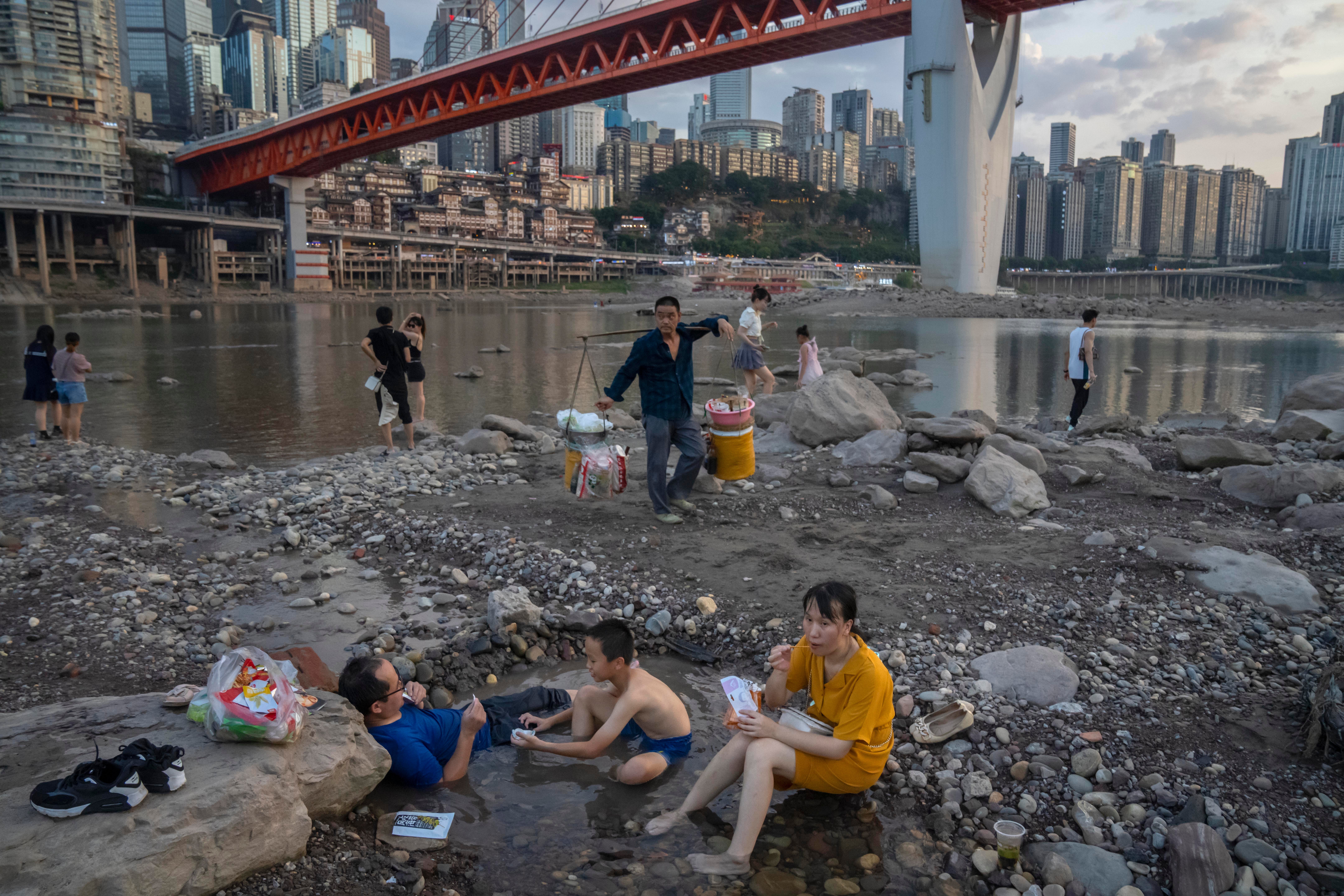 People sit in the riverbed of the Jialing on August 20. (Photo: Mark Schiefelbein, AP)