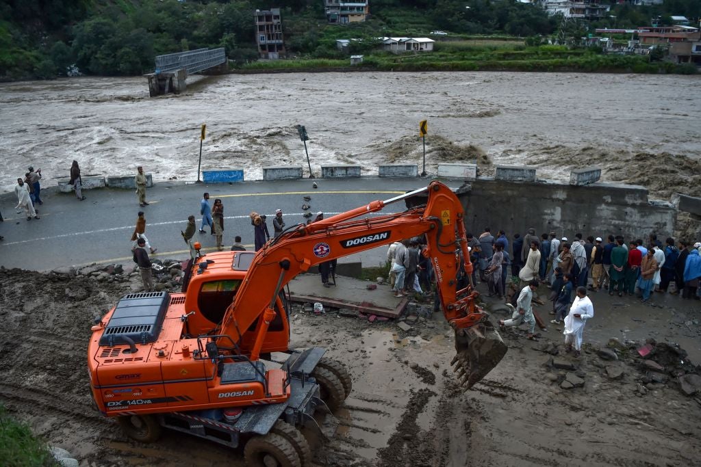 People gather next to a section of a road damaged by flood waters following heavy monsoon rains in Madian area in Pakistan's northern Swat Valley on August 27, 2022. (Photo: Abdul MAJEED / AFP, Getty Images)