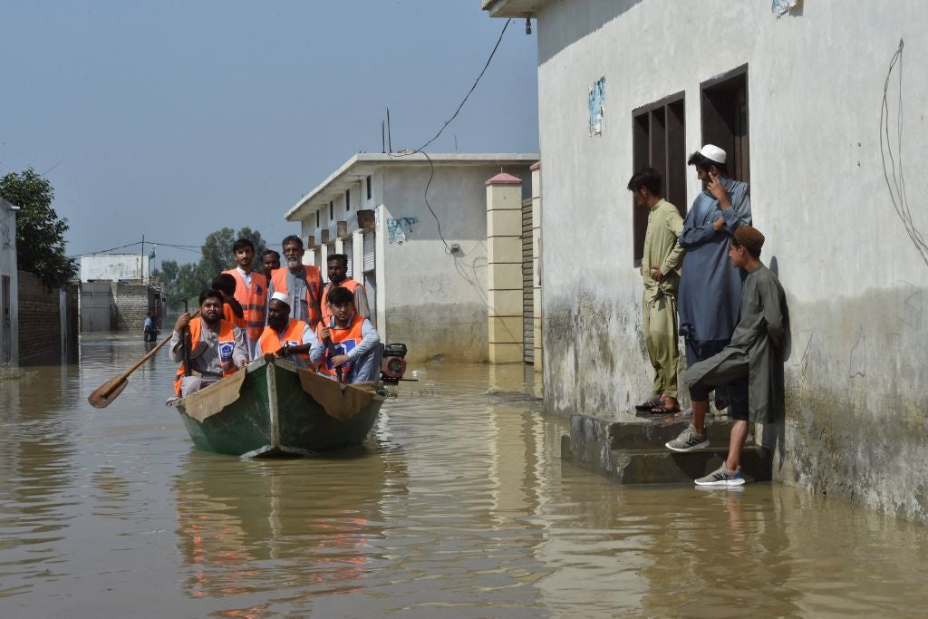 Armed members of Alkhidmat Foundation patrol on a boat at a residential area submerged in floodwater in Nowshera of Khyber Pakhtunkhwa province on August 29, 2022. (Photo: ABDUL MAJEED/AFP, Getty Images)