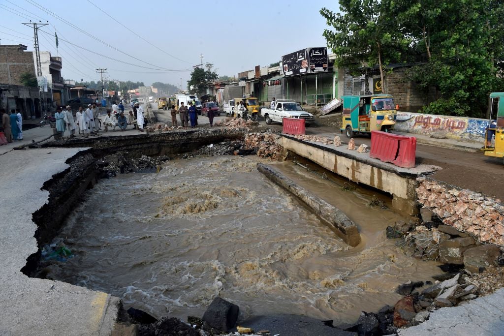Residents gather beside a road damaged by flood waters following heavy monsoon rains in Charsadda district of Khyber Pakhtunkhwa on August 29, 2022.  (Photo: Abdul MAJEED / AFP, Getty Images)