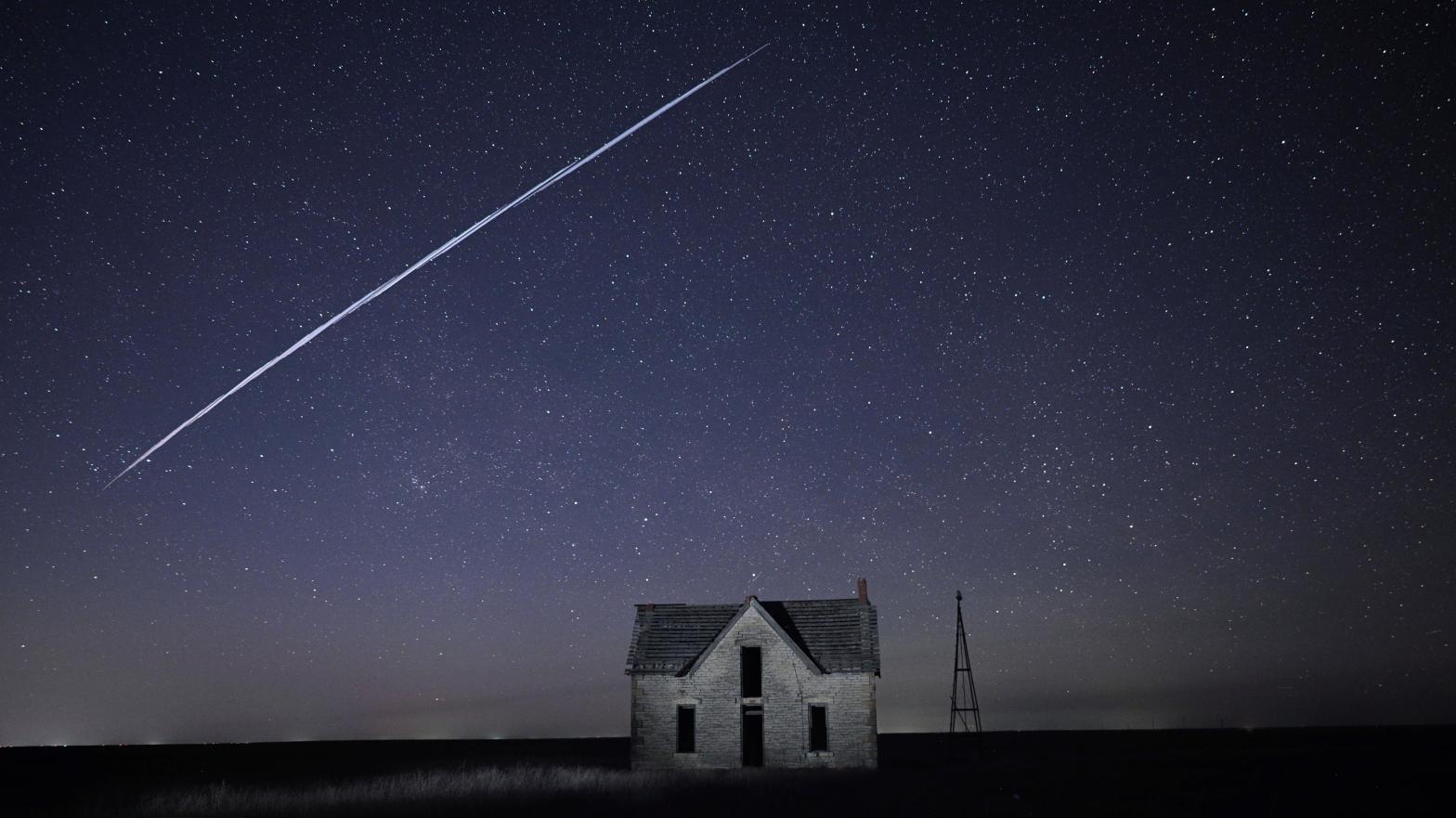 A streak of SpaceX StarLink satellites passes over an old stone house in Kansas. (Photo: Reed Hoffmann, AP)
