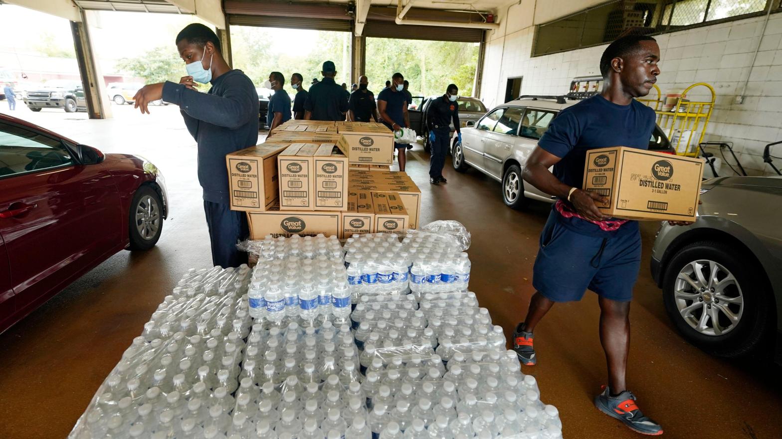 Firefighters and recruits for the Jackson, Miss., Fire Department carry cases of bottled water to residents vehicles, Aug. 18, 2022, as part of the city's response to longstanding water system problems.  (Photo: Rogelio V. Solis, AP)