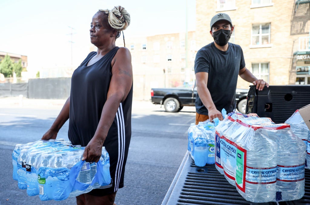 A member of the Skid Row community carries away water distributed by volunteers with Water Drop LA on September 4, 2022 as temperatures hovered around 100 degrees in Los Angeles, California.  (Photo: Mario Tama, Getty Images)