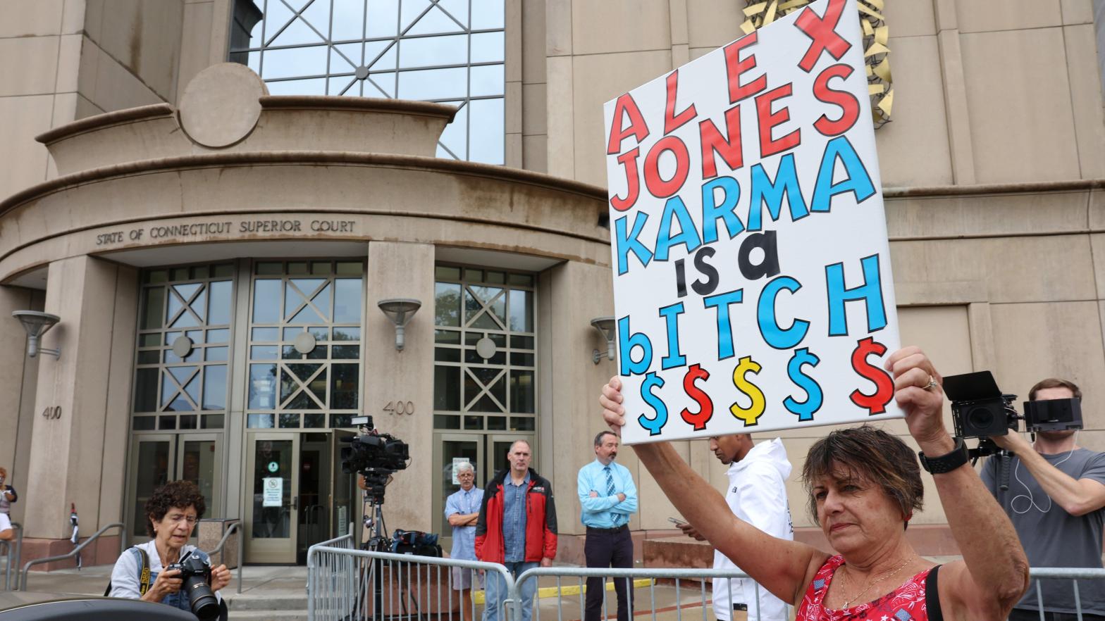 A woman holds a protest sign outside of the Waterbury Superior Court today. Alex Jones was not in attendance. (Image: Spencer Platt, Getty Images)