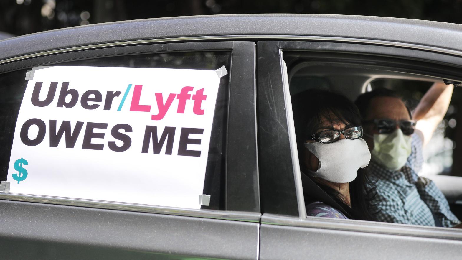 A driver and passenger wear face masks as Uber and Lyft drivers with Rideshare Drivers United and the  Transport Workers Union of America conduct a 'caravan protest' outside the California Labour Commissioner's office amidst the coronavirus pandemic on April 16, 2020 in Los Angeles, California. (Photo: Mario Tama, Getty Images)