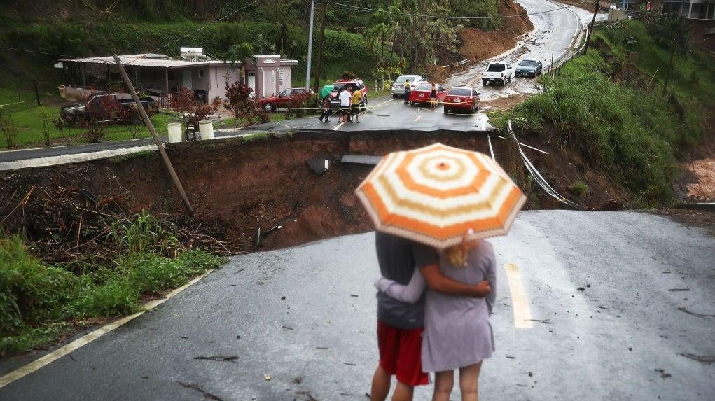 People look on at a section of a road that collapsed and continues to erode days after Hurricane Maria swept through the island on October 7, 2017 in Barranquitas, Puerto Rico. (Photo: Joe Raedle, Getty Images)