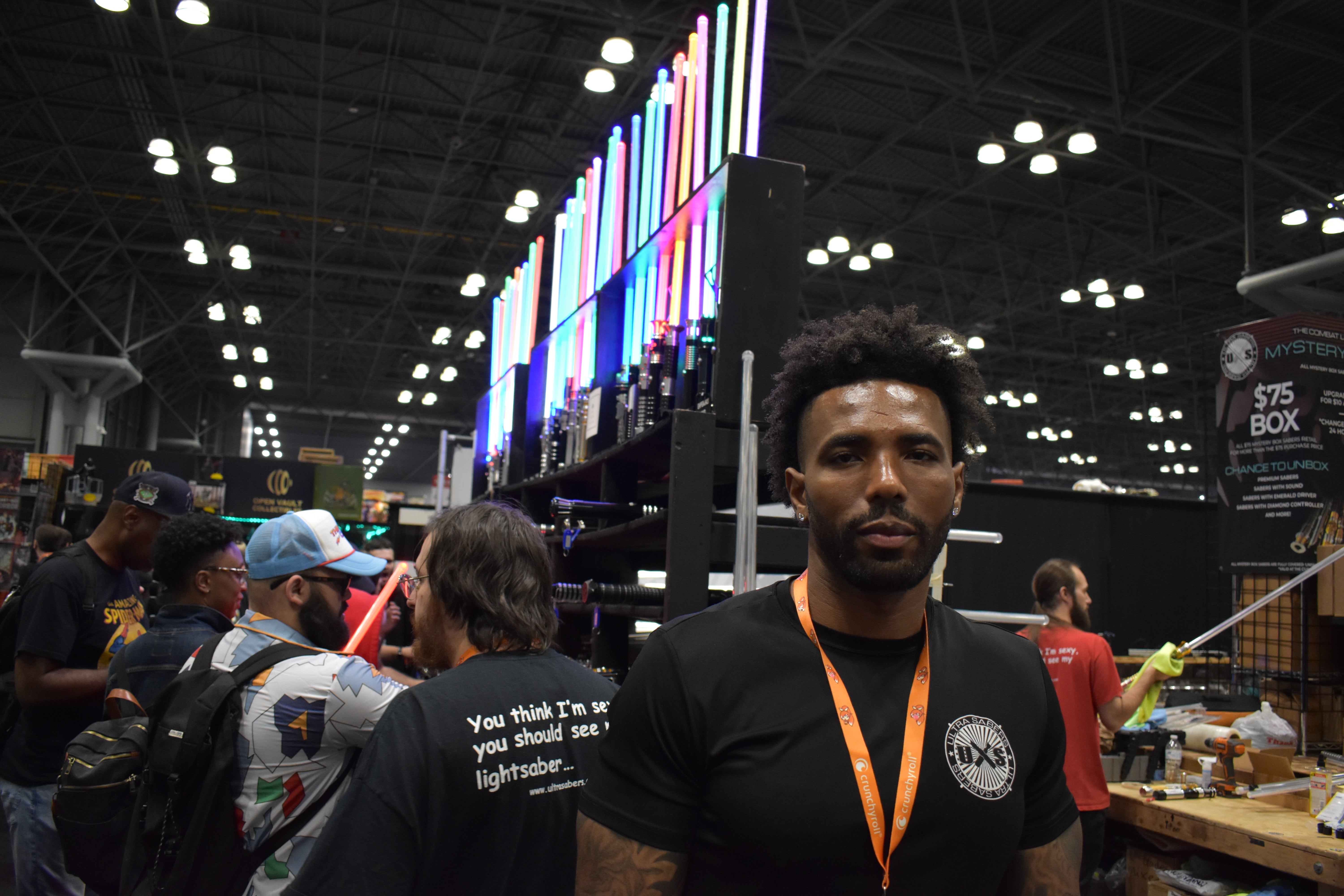 Emory Harris, the owner of Ultrasabers, stands in front of the busy booth at New York Comic Con. (Photo: Kyle Barr/io9)