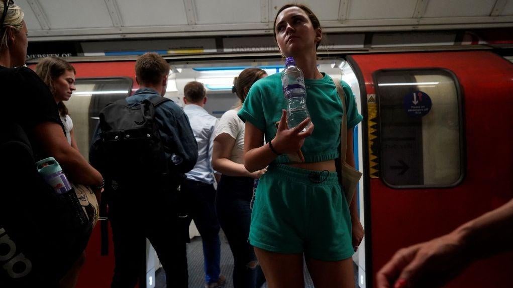 A commuter carries a bottle of water as they exit the carriage of a London Underground tube train in central London, on July 19, 2022 as the country experiences an extreme heat wave. (Photo: Niklas HALLE’N / AFP, Getty Images)