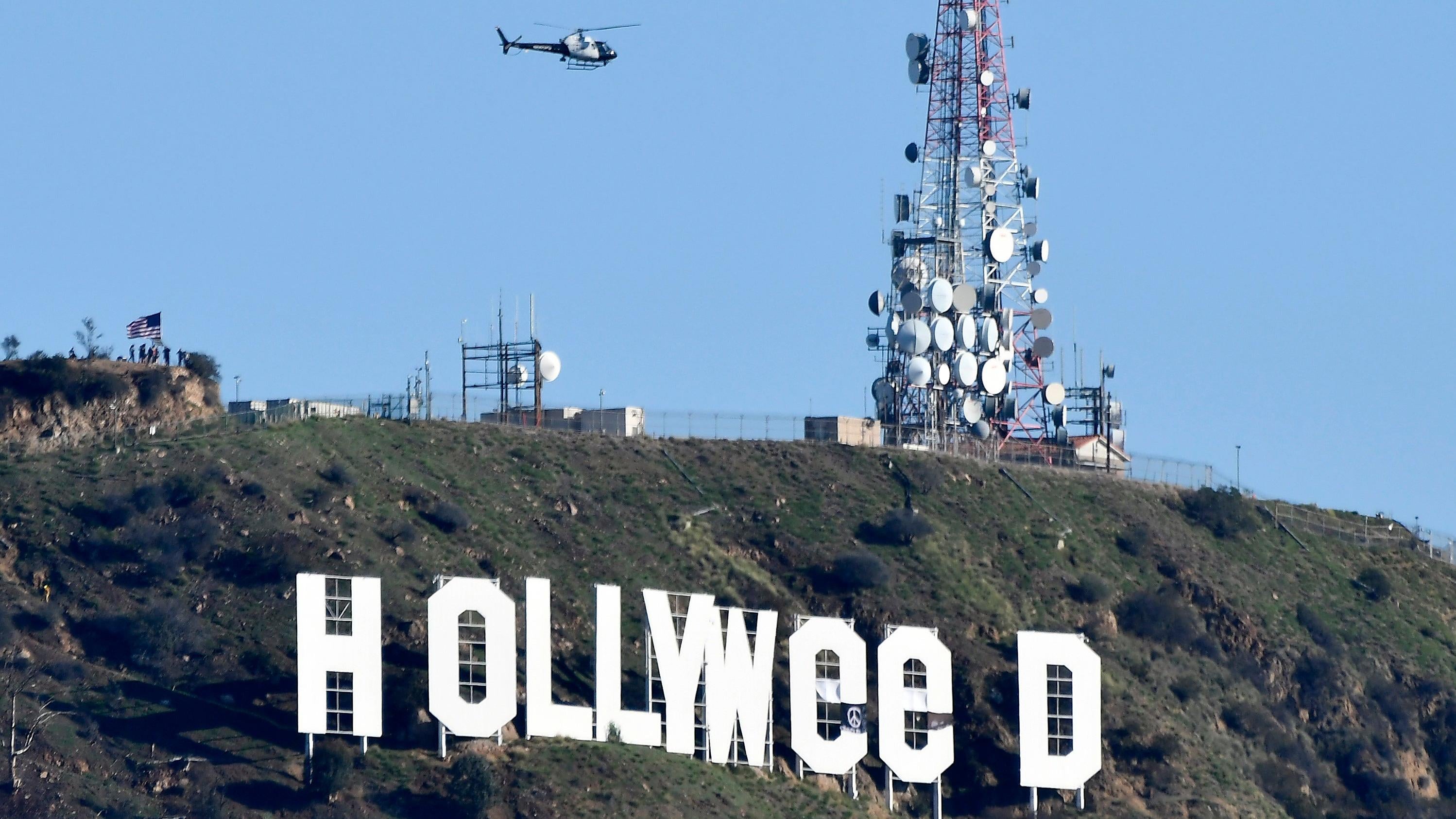 A police helicopter flies over the Hollywood sign after somebody improved it.  (Photo: GENE BLEVINS/AFP, Getty Images)