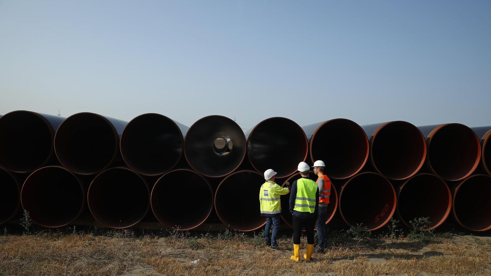 Workers stand in front of stacked pipes for a natural gas pipeline. (Photo: Sean Gallup, Getty Images)