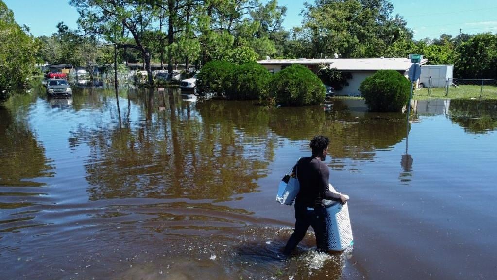 A man walks through a flooded street with his belongings in the Orlovista neighbourhood following Hurricane Ian on October 1, 2022 in Orlando, Florida. (Photo: BRYAN R. SMITH/AFP, Getty Images)