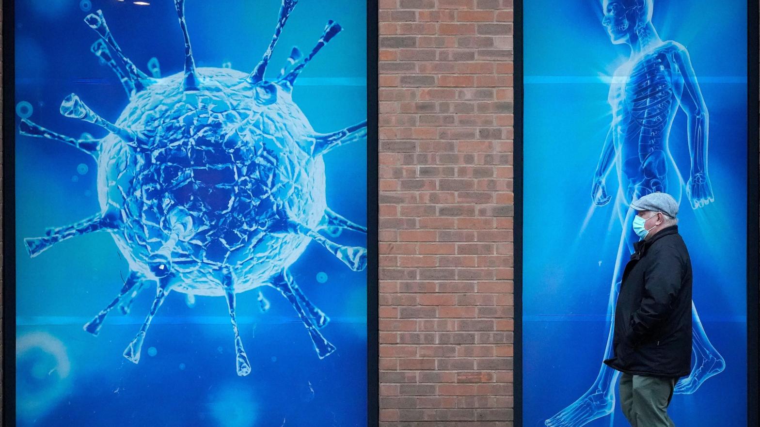 A man wearing a protective face mask walks past an illustration of a virus outside Oldham Regional Science Centre on November 24, 2020 in Oldham, United Kingdom. (Photo: Christopher Furlong, Getty Images)