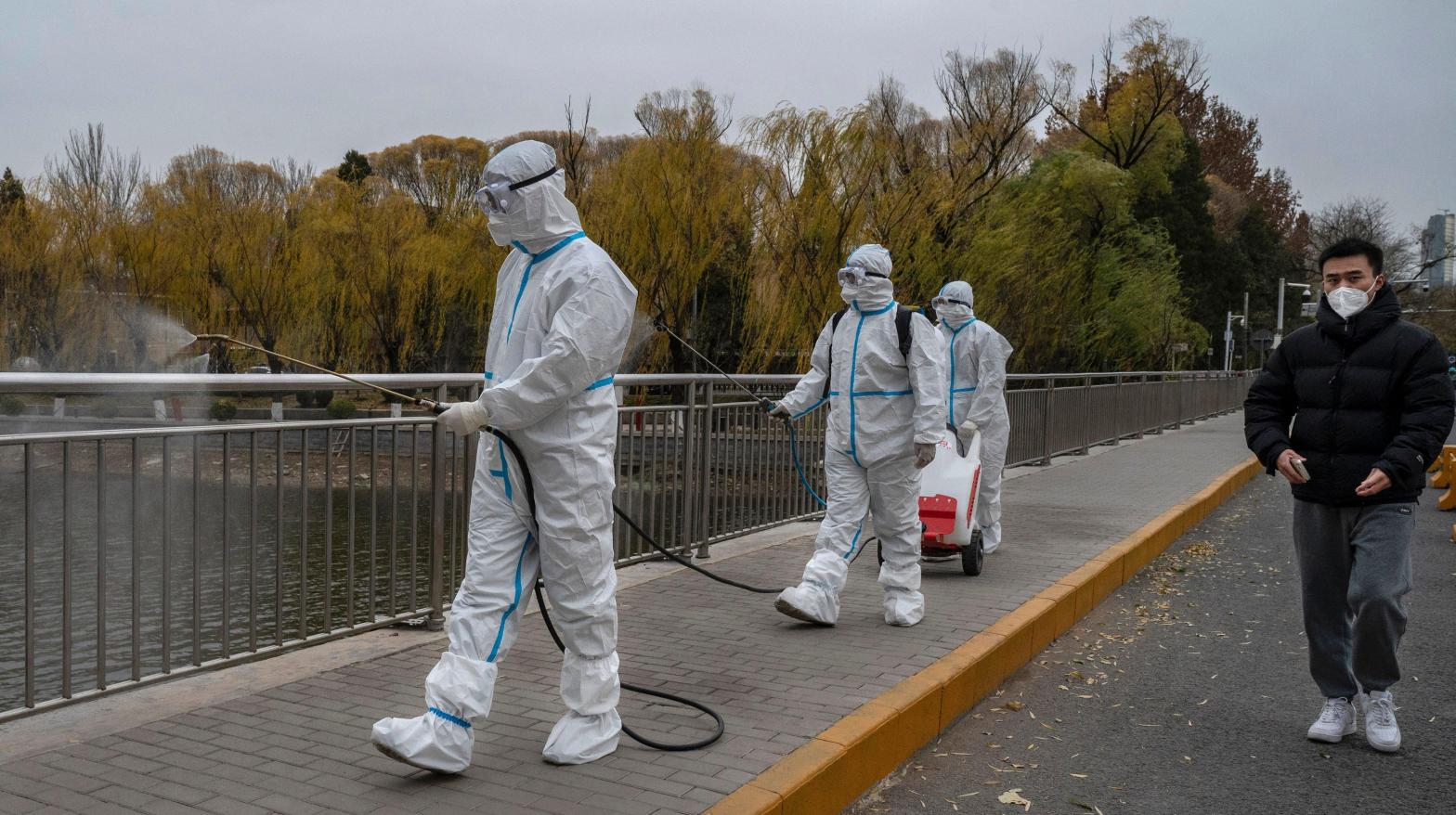 Epidemic control workers wear PPE to protect against the spread of covid-19 as they disinfect an area on the Liangma River, a popular spot for local residents and the site of a protest against covid measures the day before, on November 28, 2022  (Photo: Kevin Frayer, Getty Images)