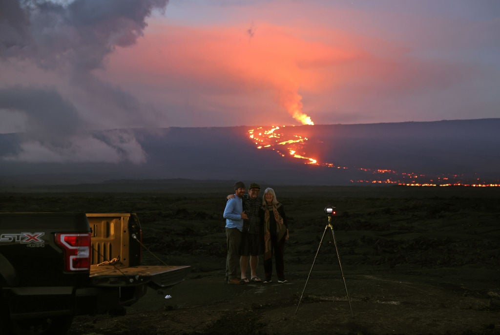 A group of people take a photo as the Mauna Loa volcano erupts behind them on December 04, 2022 near Hilo, Hawaii. (Photo: Justin Sullivan, Getty Images)
