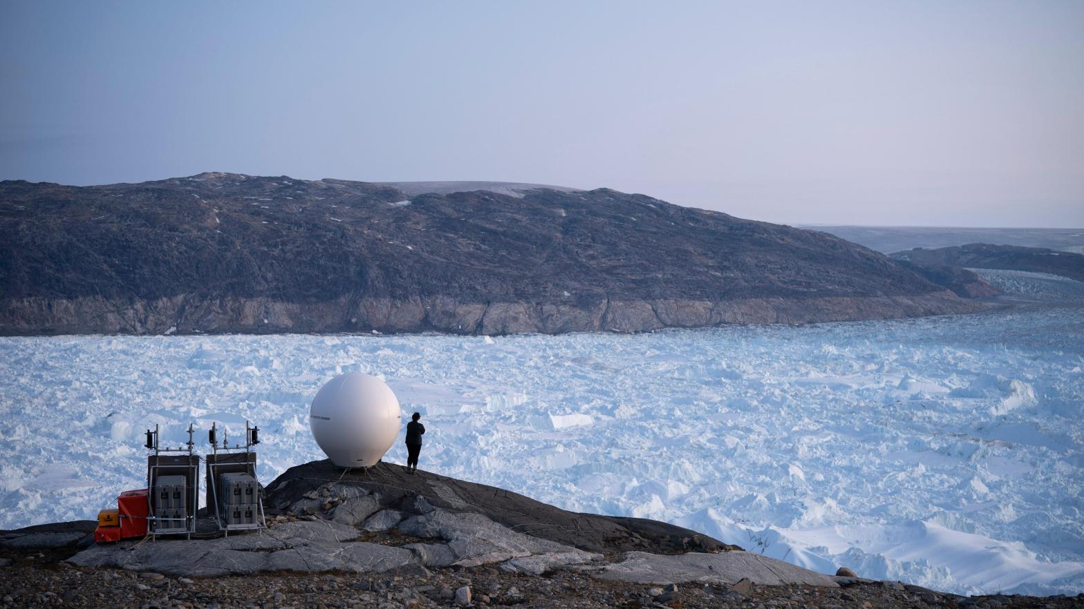 A person stands next to an antenna at the Helheim glacier in Greenland. (Photo: Felipe Dana, AP)