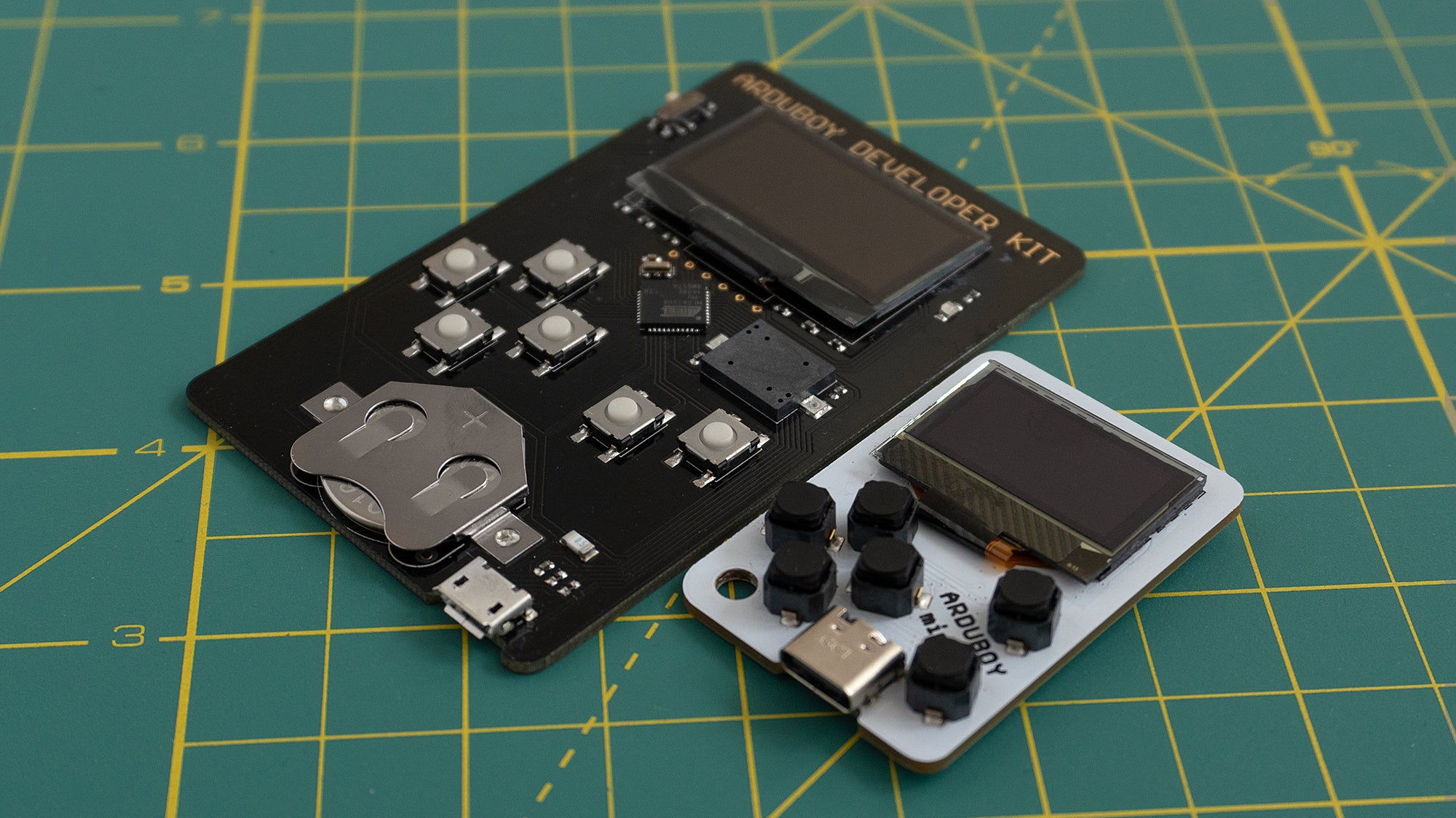 The Arduboy Mini (right) compared to the Arduboy Development Kit (left) which both feature a caseless design with exposed electronics. (Photo: Andrew Liszewski | Gizmodo)