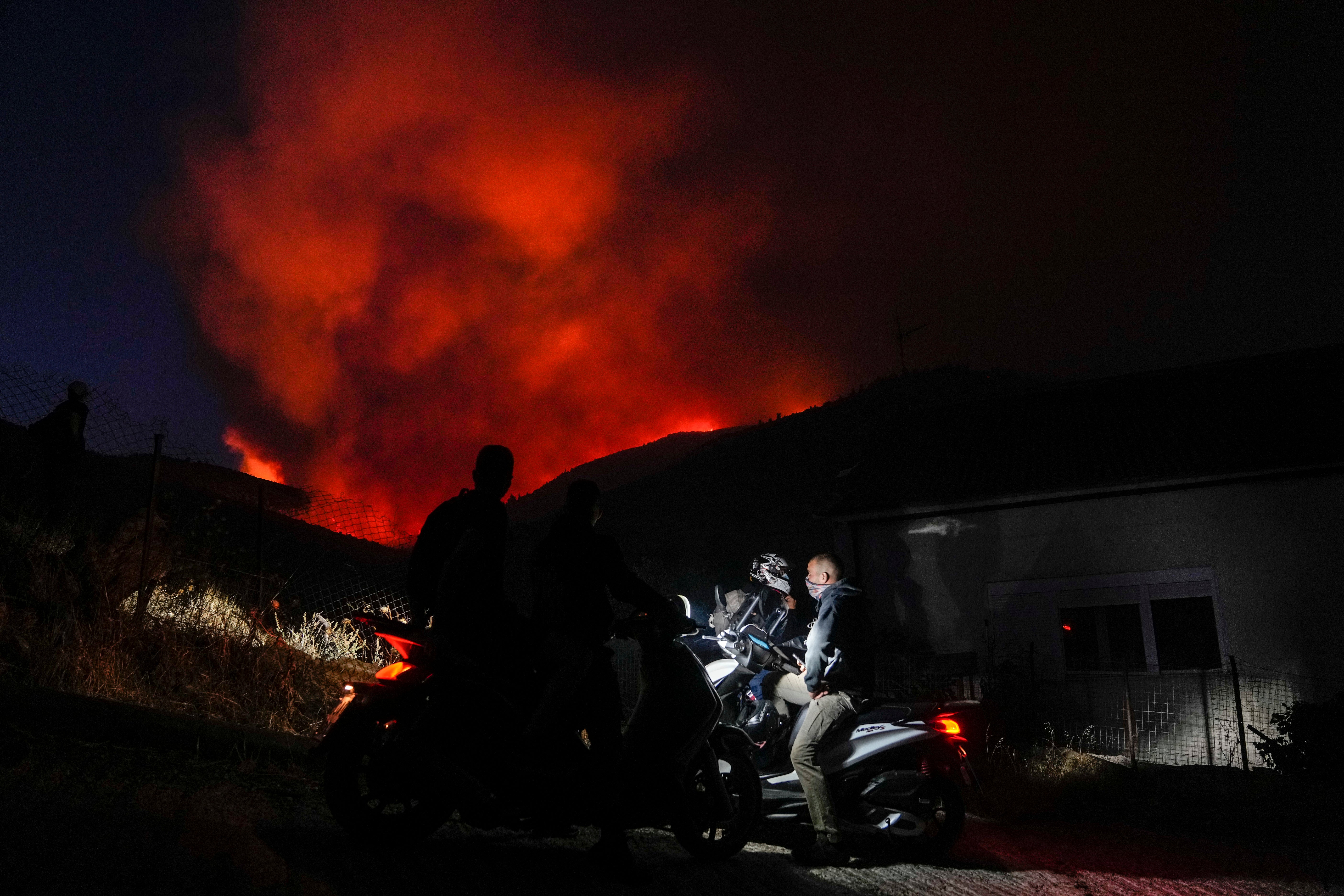 Men on motorcycles watch a fire at Penteli, Greece, on Tuesday, July 19, 2022. (Photo: Thanassis Stavrakis, AP)