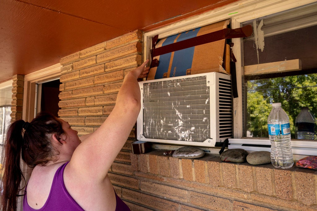 Kirstie Allemand arranges cardboard above an air conditioning unit in her window during soaring temperatures on July 28, 2022 in Ellensburg, Washington. (Photo: David Ryder, Getty Images)