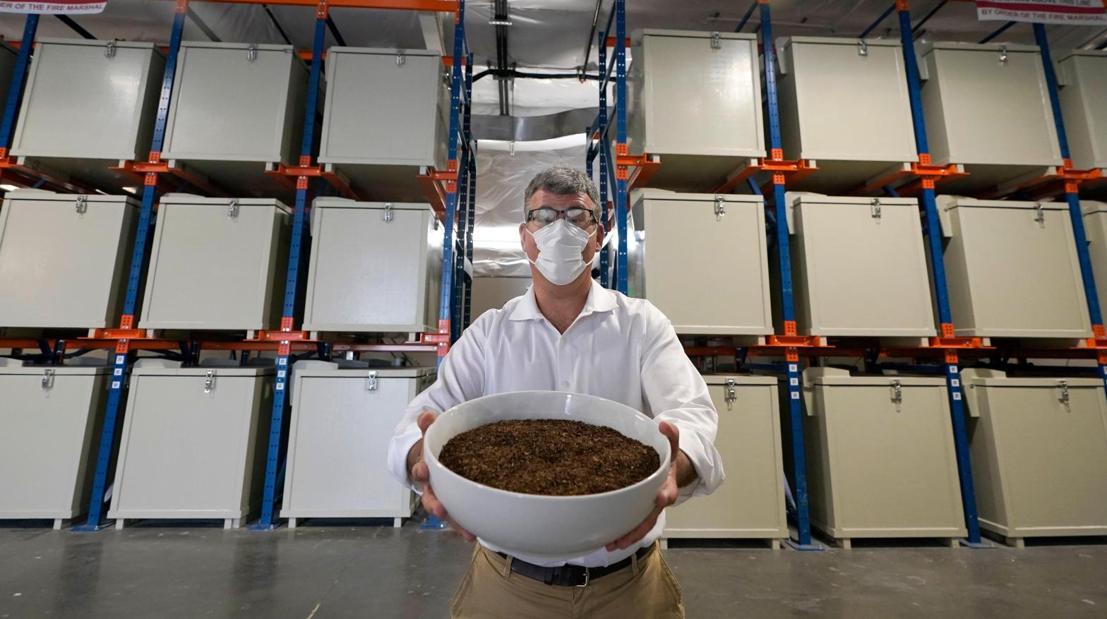 Micah Truman, CEO of a Washington-based human composting company, poses with a photo of compost made from animal remains to illustrate the process. (Photo: Ted S. Warren, AP)
