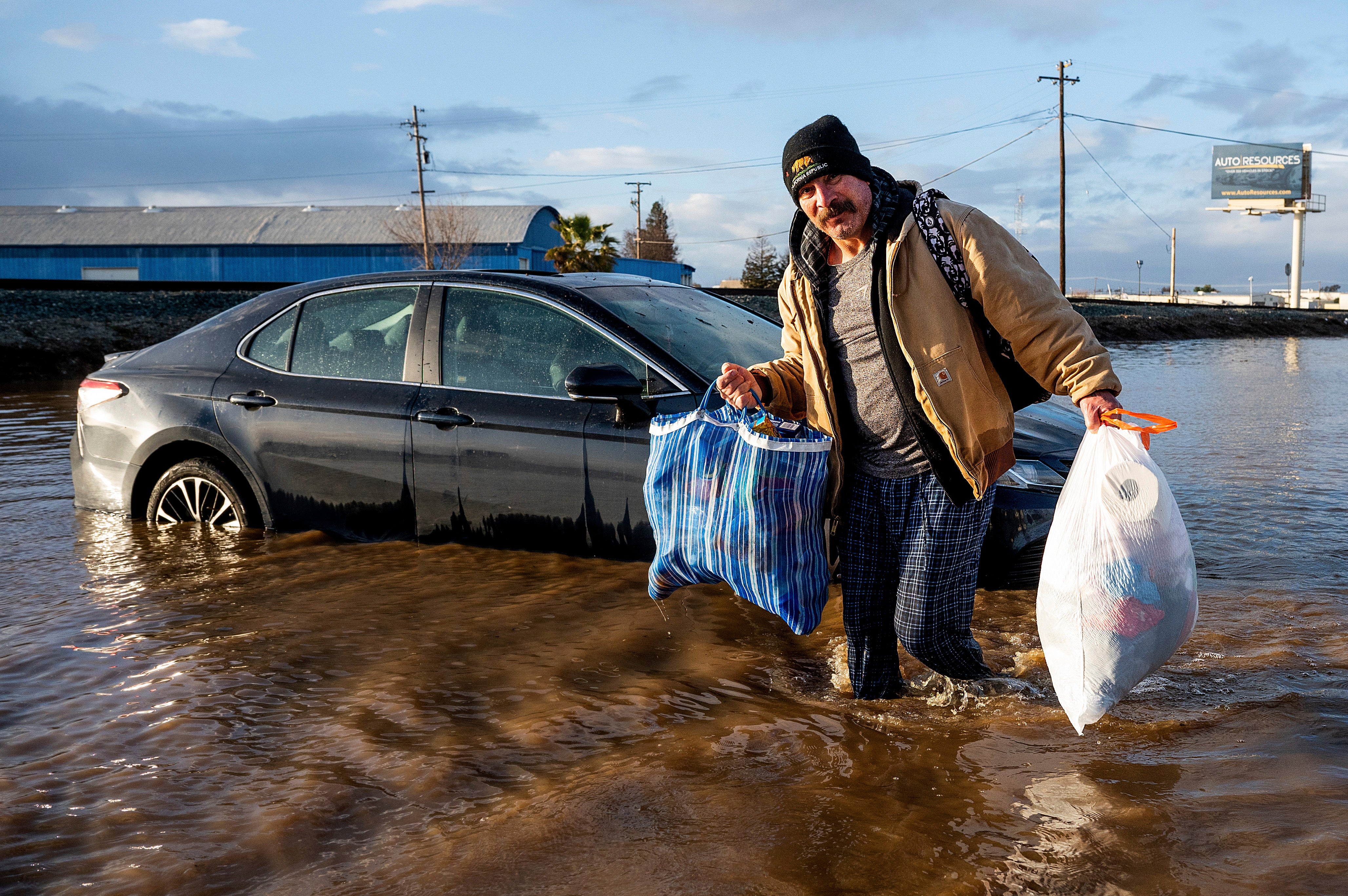  Jesus Torres, whose home in Merced flooded, carries his belongings on Tuesday, January 10. (Photo: Noah Berger, AP)
