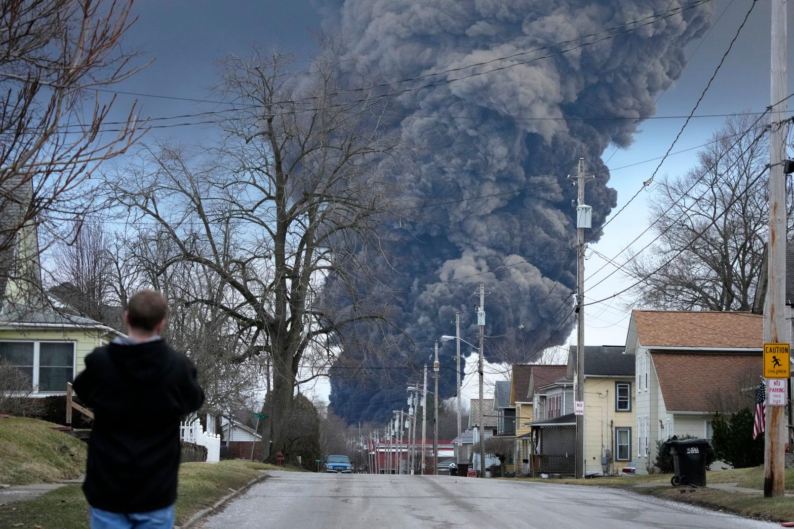 A man takes photos as a black plume rises over East Palestine, Ohio, as a result of a controlled detonation of a portion of the derailed Norfolk Southern train, Feb. 6, 2023. (Photo: AP Photo/Gene J. Puskar, AP)