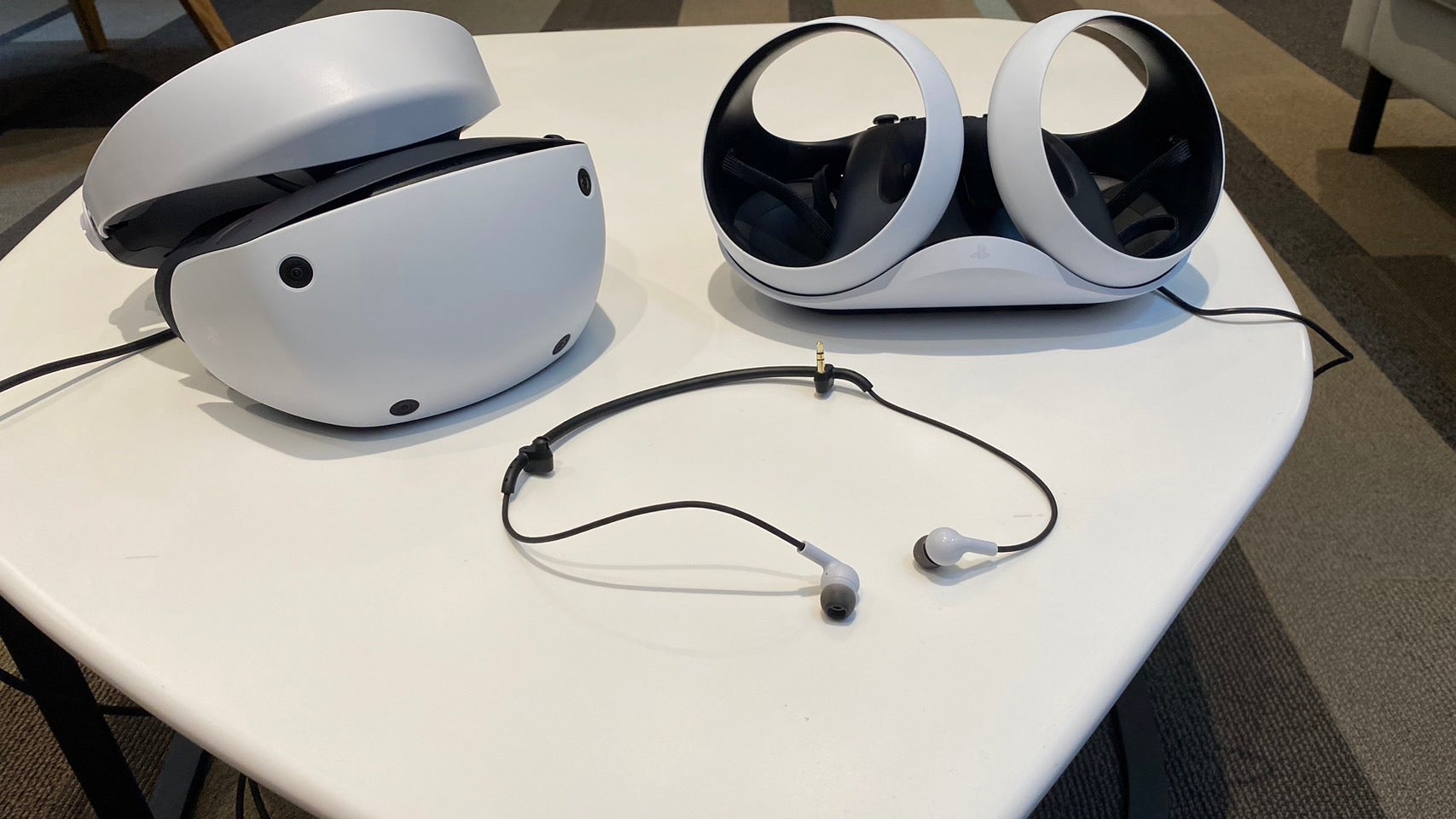 The Sony PSVR 2 pictured next to its earbuds and optional charging cradle (Photo: Michelle Ehrhardt / Gizmodo)