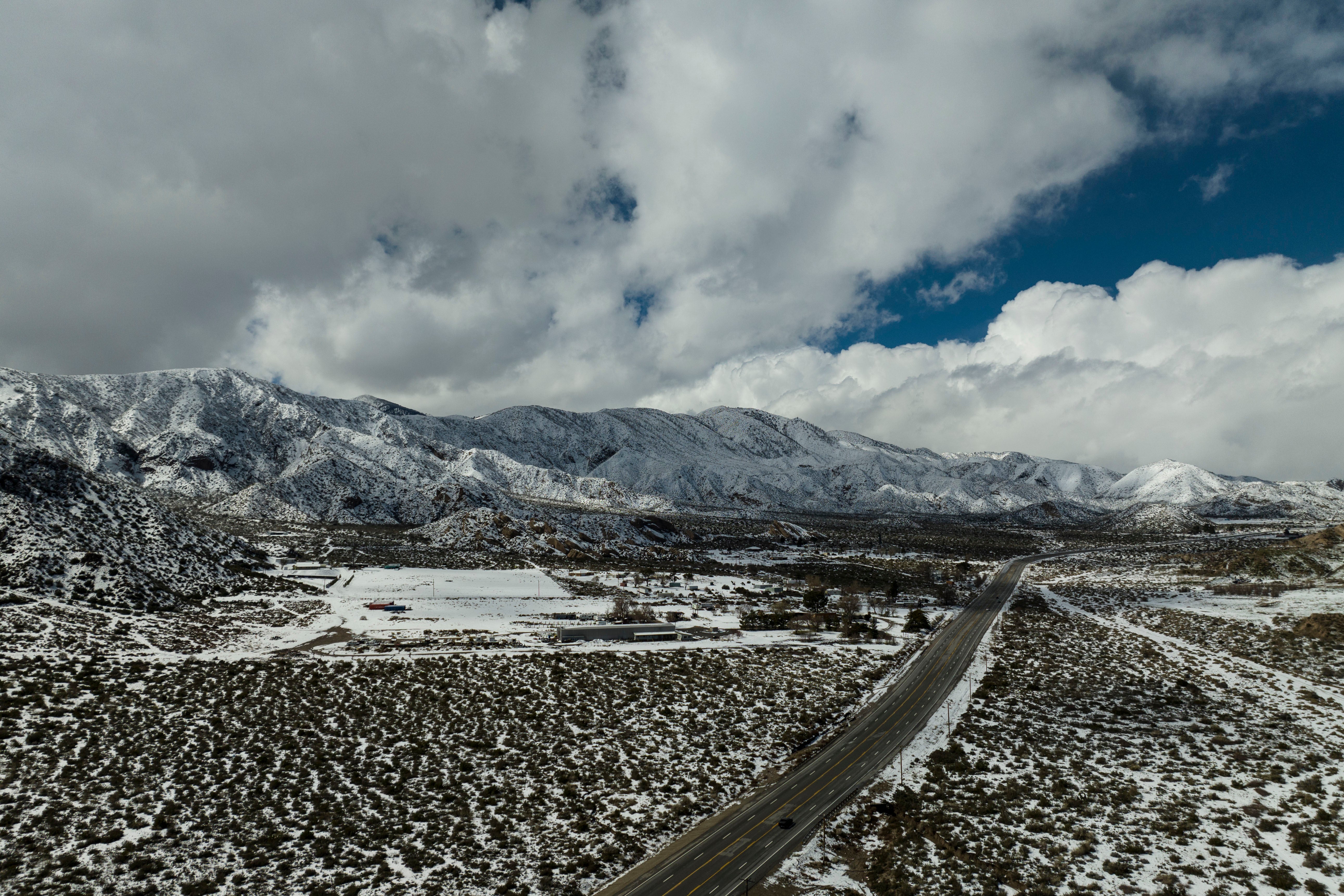 Clouds hover over snow-covered mountains as a car drives along a state route near Phelan, California on Wednesday, March 1, 2023. (Photo: Jae C. Hong, AP)